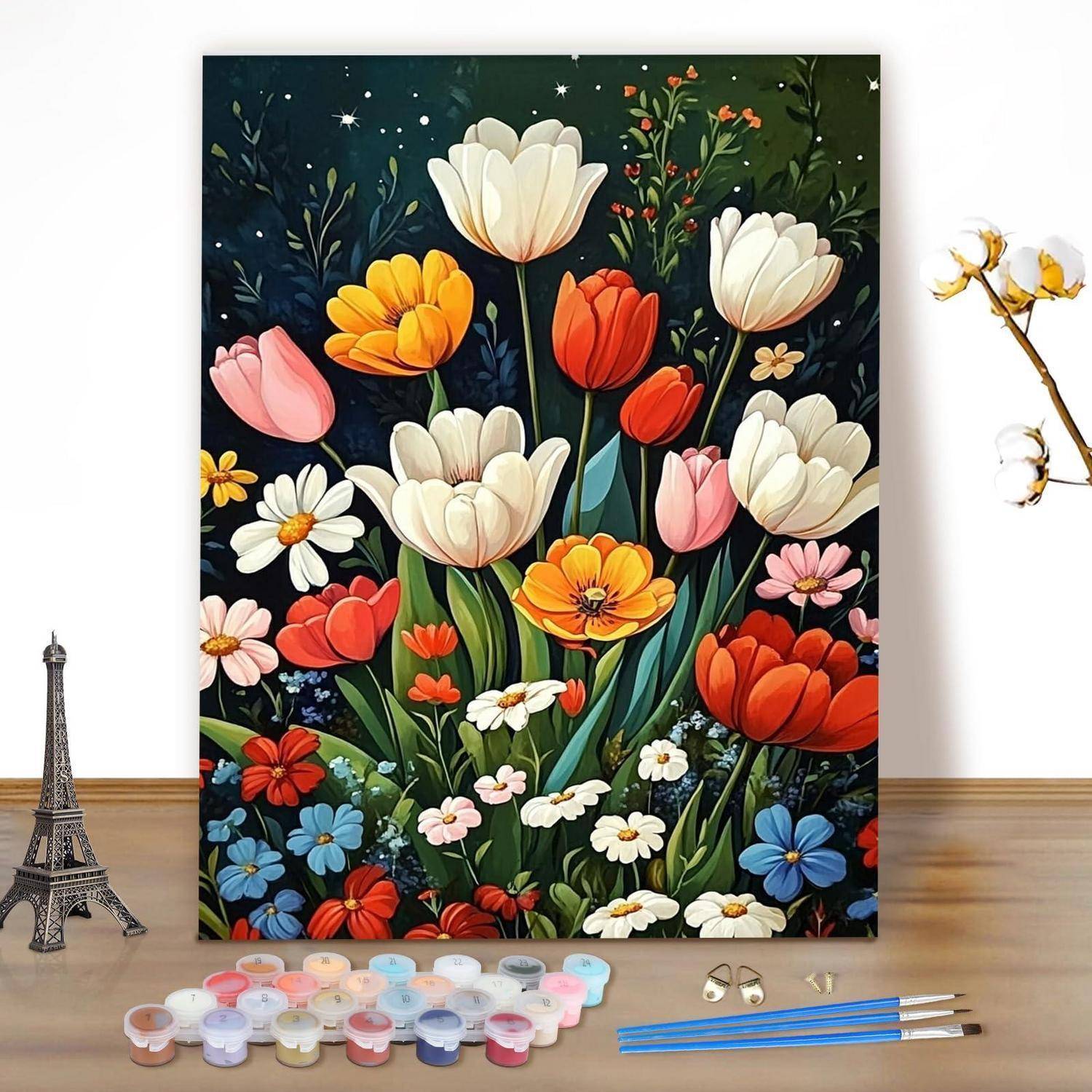 Helles Blumengemälde mit Tulpen und Gänseblümchen auf einer Leinwand, dargestellt mit Malzubehör, Pinseln und einem kleinen Eiffelturm-Modell auf einem Tisch.