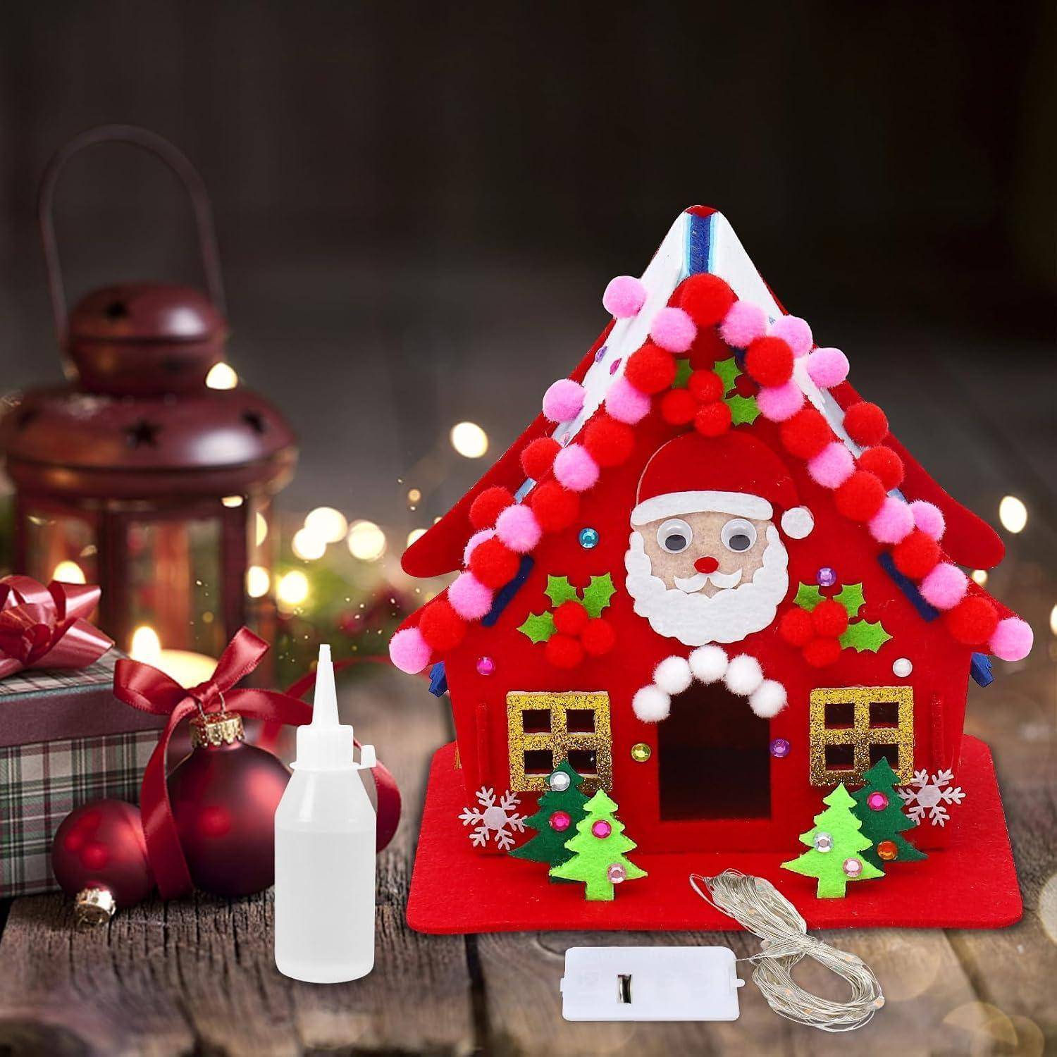 Ein kleines rotes Weihnachtsmann-Filzhaus-Handwerk mit Pompom-Borte, das auf einer Holzoberfläche neben einer Leimflasche und dekorativen Weihnachtsartikeln sitzt.