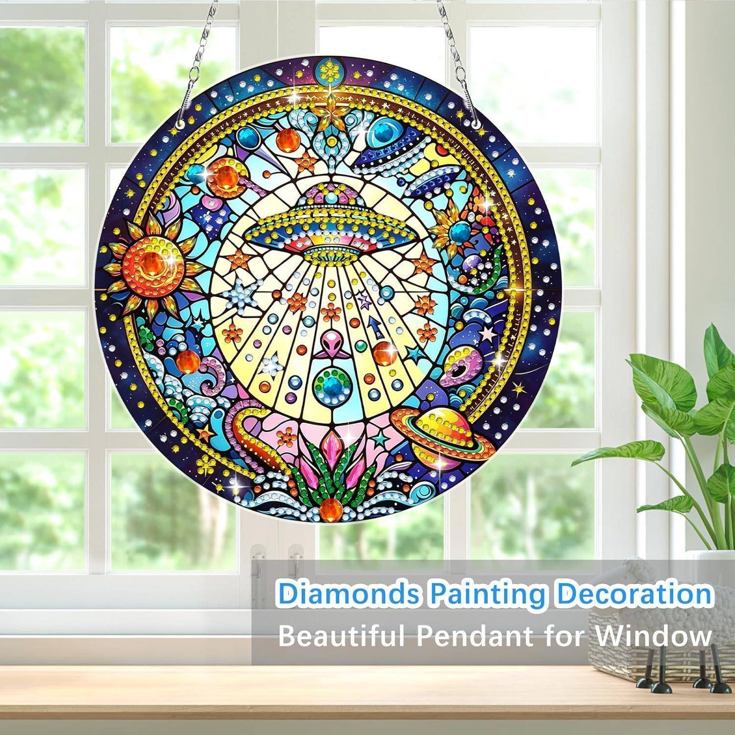 Bunte runde Buntglas-ähnliche hängende Fensterdekoration mit einer kosmischen UFO-Szene und Planeten, gezeigt vor einem hellen Fenster.