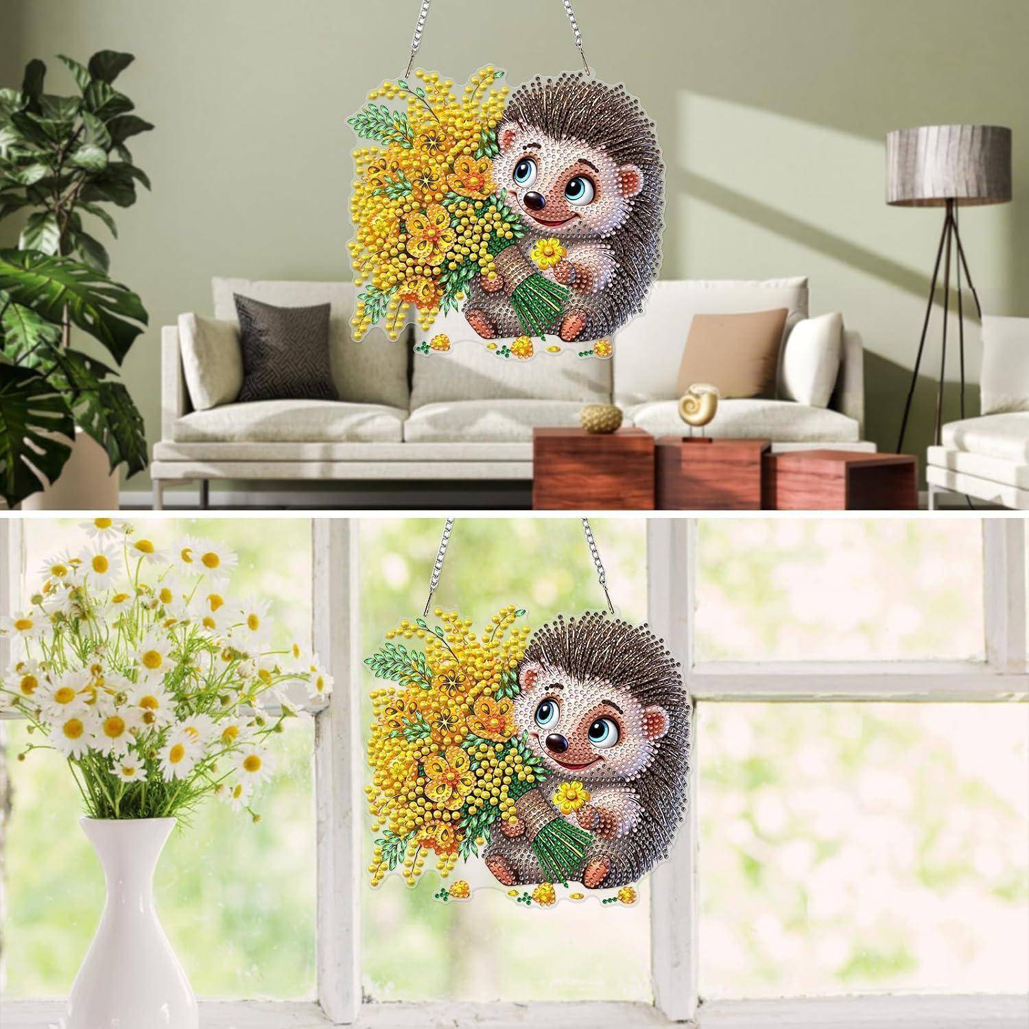 Ein hängender Kristall-Igel-Schmuck, der gelbe Blumen hält, gezeigt in einem Wohnzimmer und an einem Fenster als dekorative Lichtfangvorrichtung.