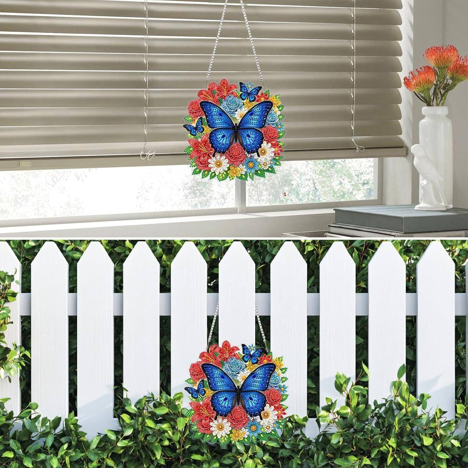 Buntes Schmetterlings-Blüten-Hängeglas, das an einem Fenster und einem weißen Lattenzaun in Innen- und Außenumgebungen angebracht ist.