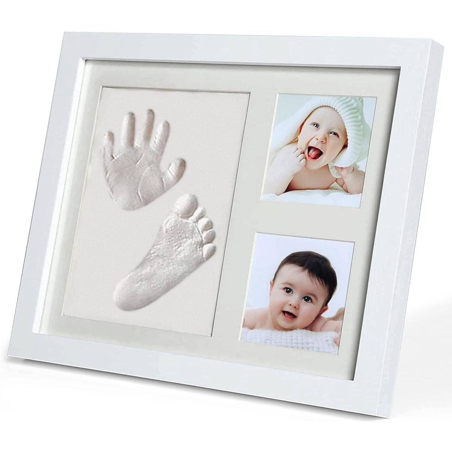 Weißer Baby-Erinnerungsrahmen mit Gips-Hand- und Fußabdruckabgüssen neben zwei Säuglingsfotos.
