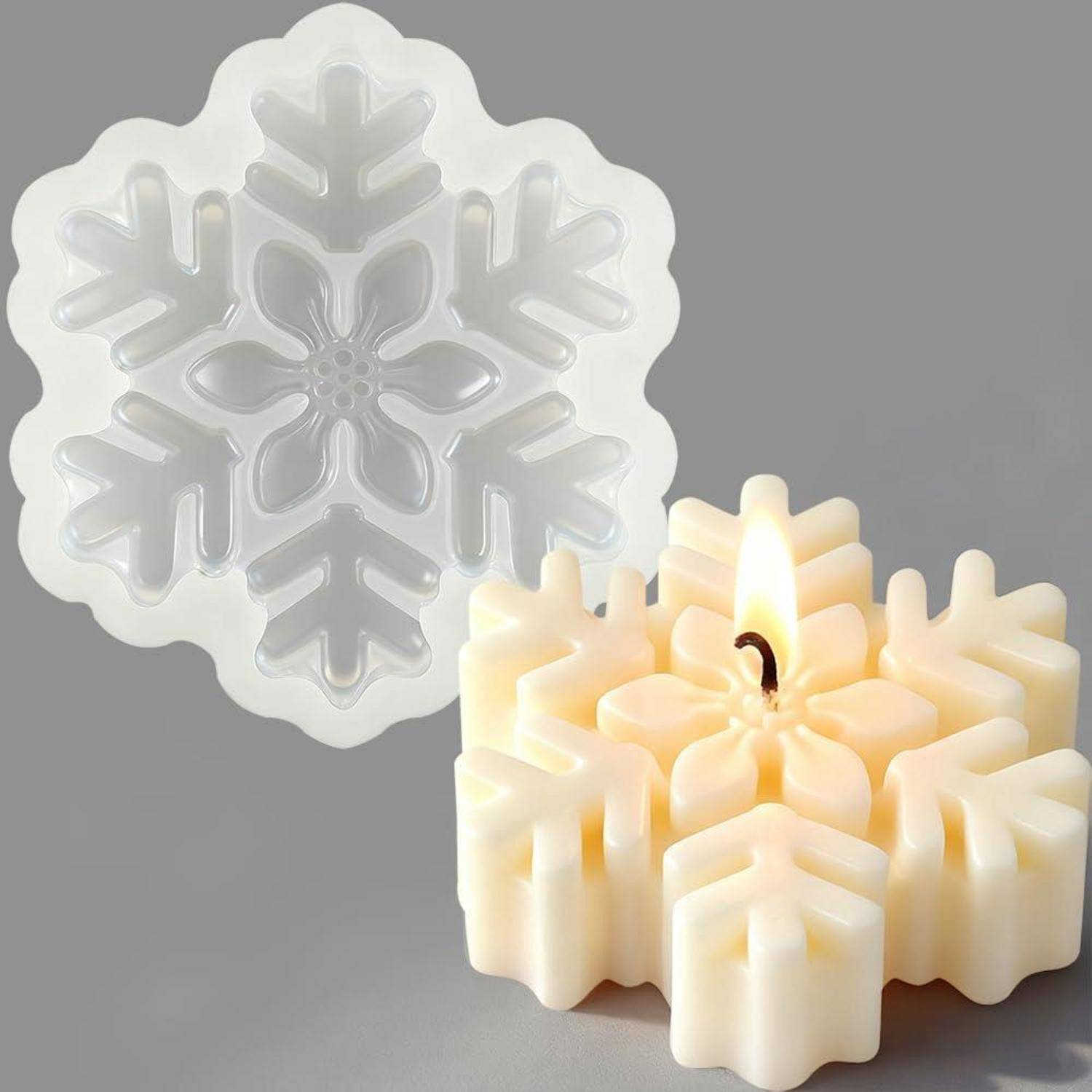 Schneeflockenförmige Kerzenform, die als durchscheinende Form neben einer fertigen cremefarbenen Schneeflockenkerze mit brennendem Docht auf grauem Hintergrund dargestellt wird.