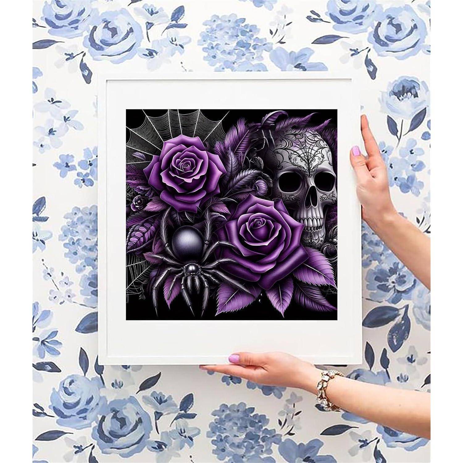 Hände halten einen Kunstdruck im gotischen Stil mit weißem Rahmen, auf dem violette Rosen, ein Schädel, eine Spinne und ein Spinnennetz auf einem blumigen Tapetenhintergrund zu sehen sind.