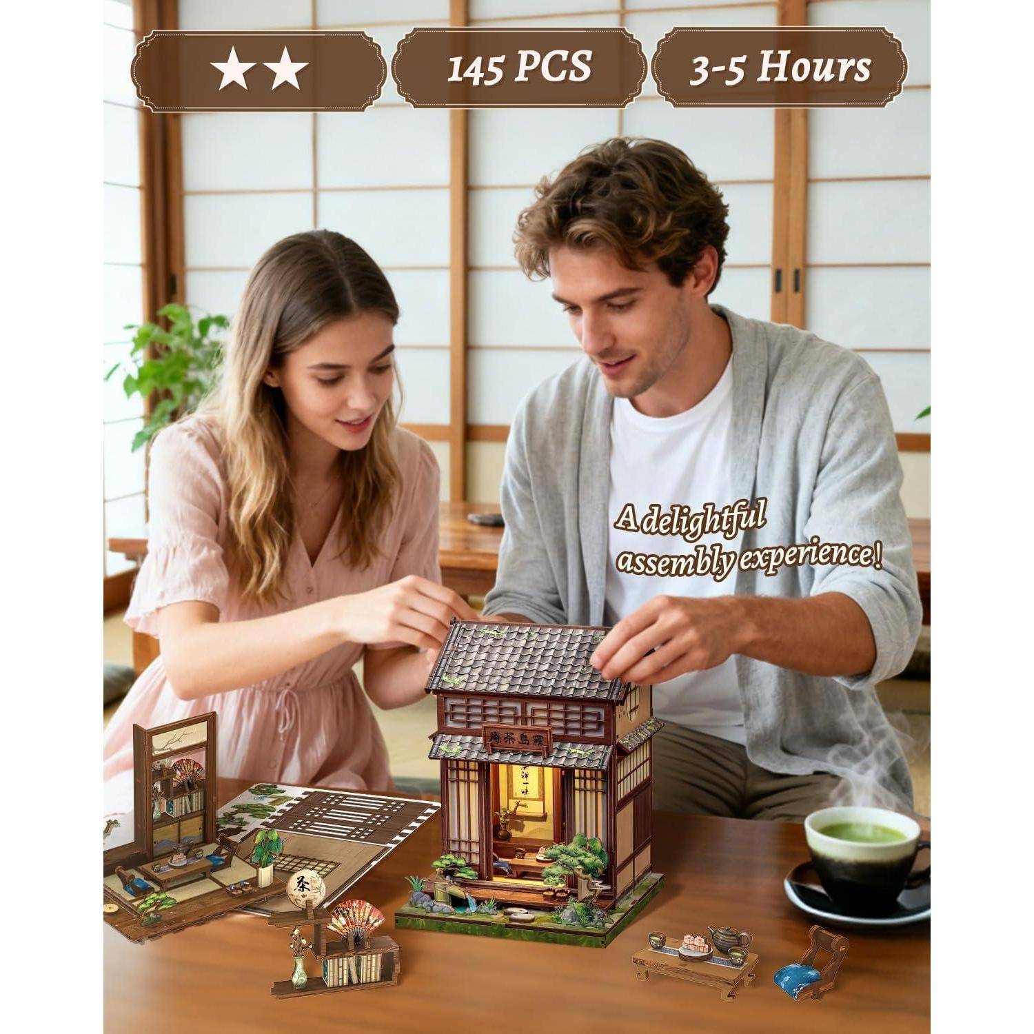 Ein Paar montiert ein Miniatur-Hausmodellbausatz an einem Tisch; der Kartontext sagt „145 TEILE