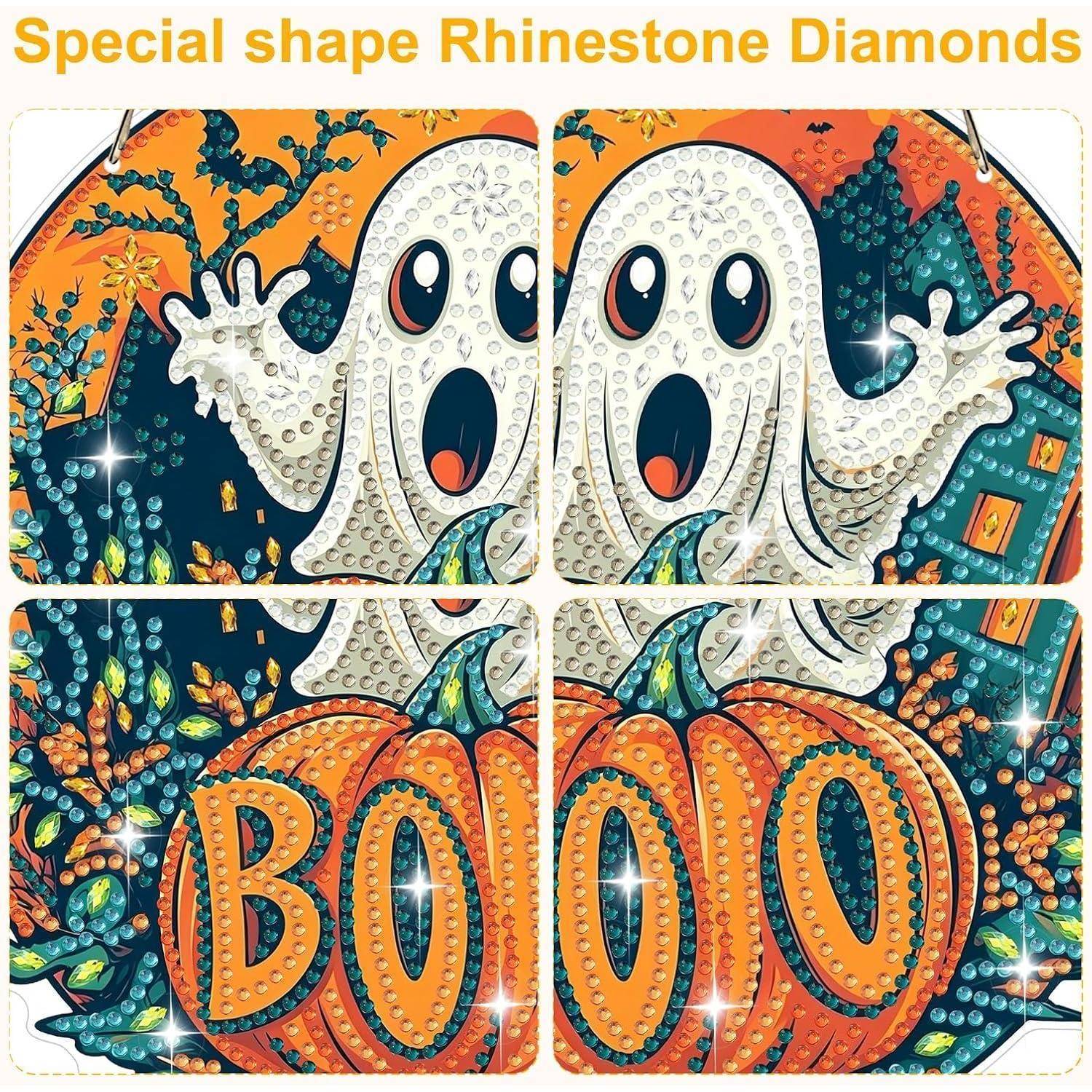 Halloween-Kunstwerk mit Strass und Diamanten, das zwei Geistergesichter über geschnitzten orangefarbenen Kürbissen zeigt, mit dem Wort „BOO