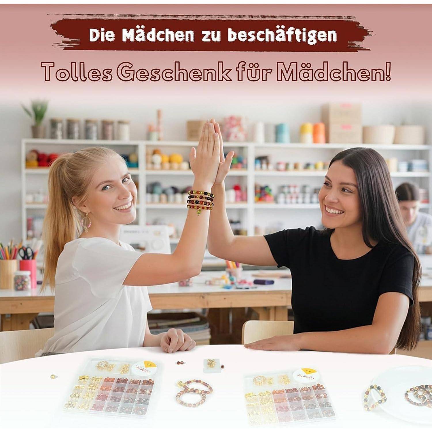 Zwei Mädchen geben sich ein High-Five an einem Basteltisch in einem Perlenherstellungs-Workshop, mit deutschem Text der lautet „Die Mädchen zu beschäftigen
