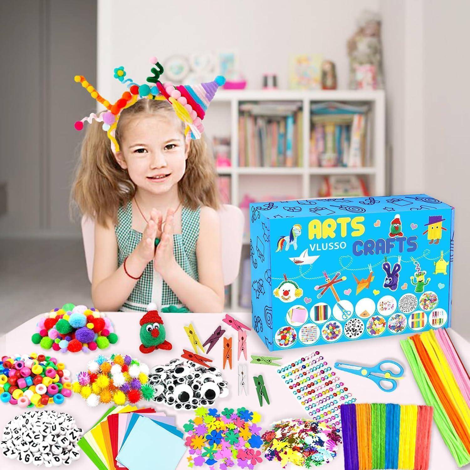 Junges Mädchen mit buntem Bastelkopfband sitzt an einem Tisch, umgeben von Bastel- und Handwerksmaterialien und einem verpackten „ARTS CRAFTS