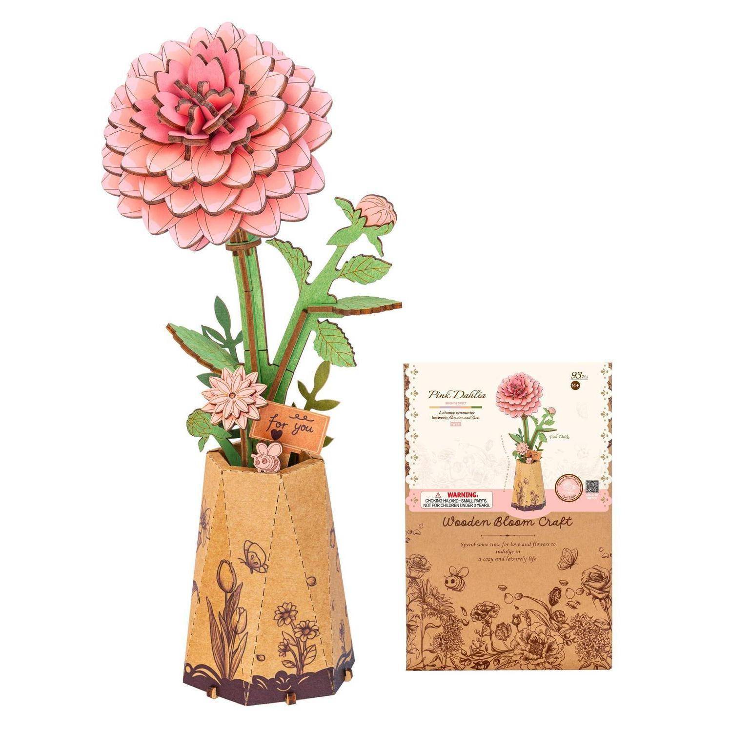 Rosa hölzerne Blütenblume aus Holz in einem sechseckigen braunen Ständer, dargestellt neben ihrer Produktverpackung.