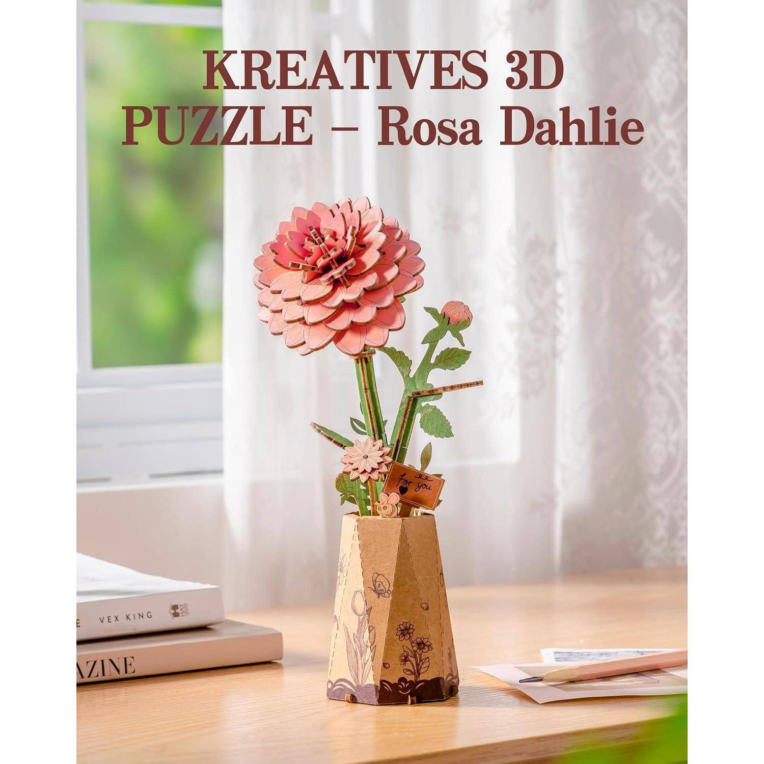 3D-Puzzlehandwerk einer rosa Dahlie in einer dekorativen Vase auf einem Tisch mit dem Titel „KREATIVES 3D PUZZLE – Rosa Dahlie