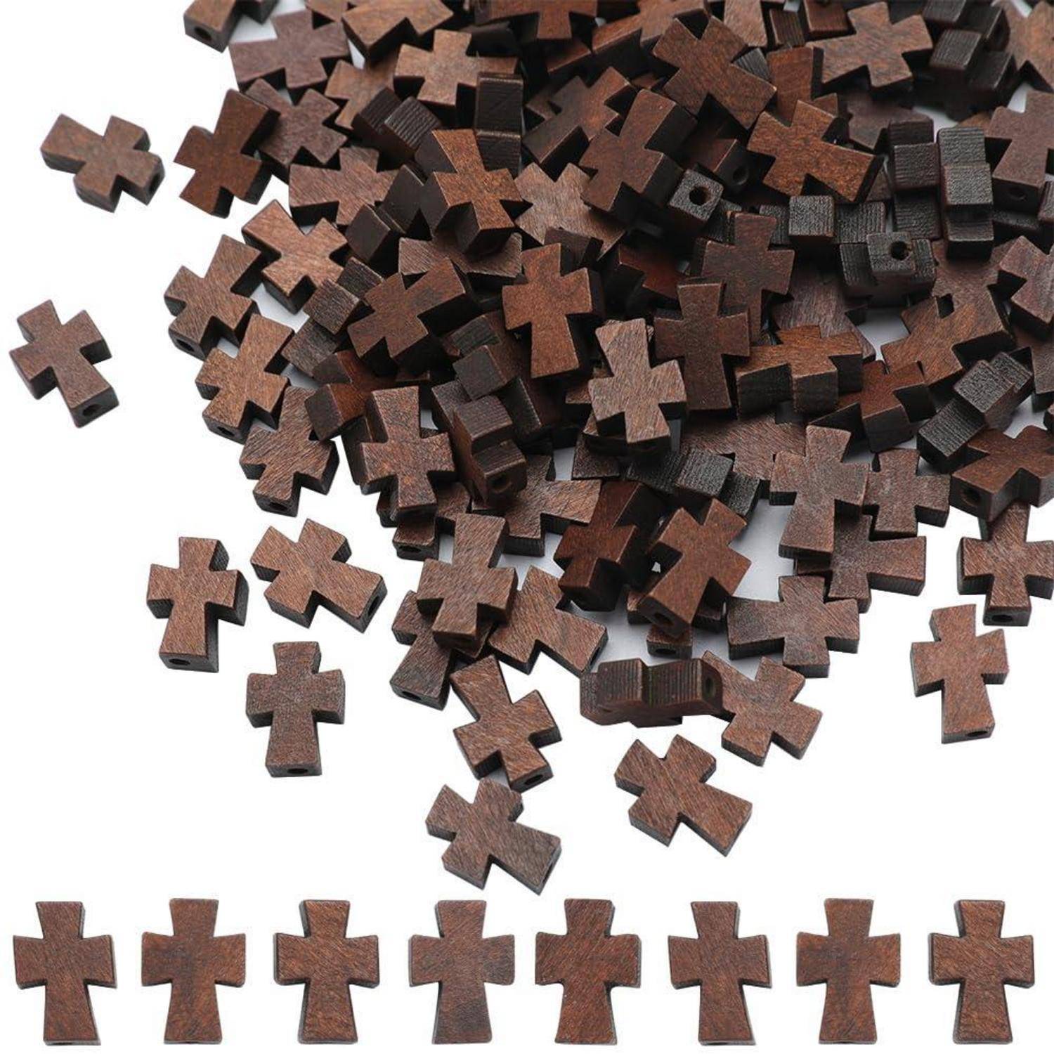 Haufen von kleinen dunklen Holzkreuzen in Kreuzform, verstreut auf weißem Hintergrund, mit einer ordentlichen Reihe von Kreuzen, die entlang des unteren Randes aufgereiht sind.