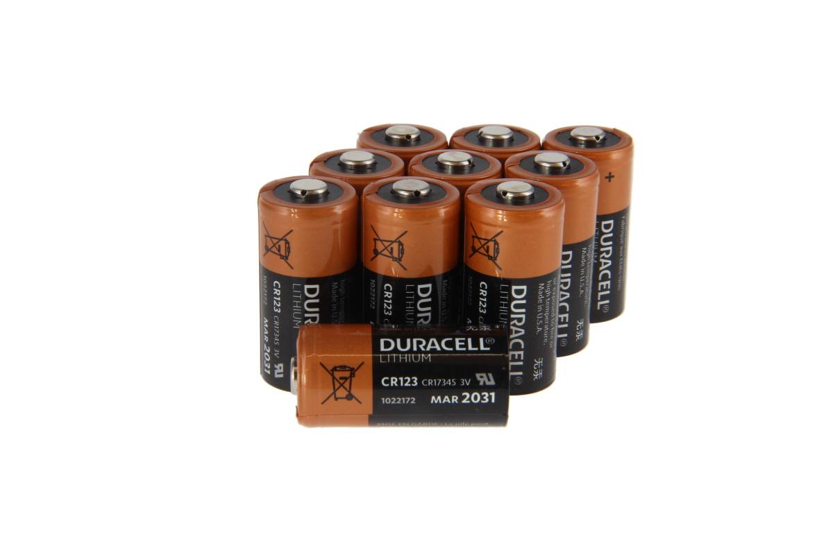 Eine Gruppe von Duracell Lithium CR123A Batterien, die zusammen auf weißem Hintergrund gestapelt sind.