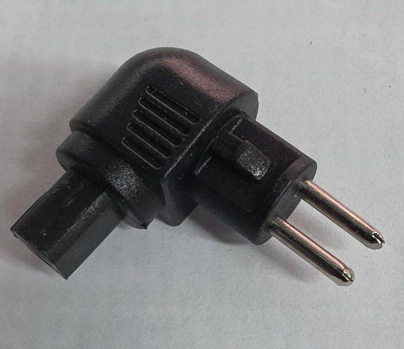 Adapter für Stromstecker mit rechtem Winkel und zwei Kontakten auf einer einfachen grauen Oberfläche.