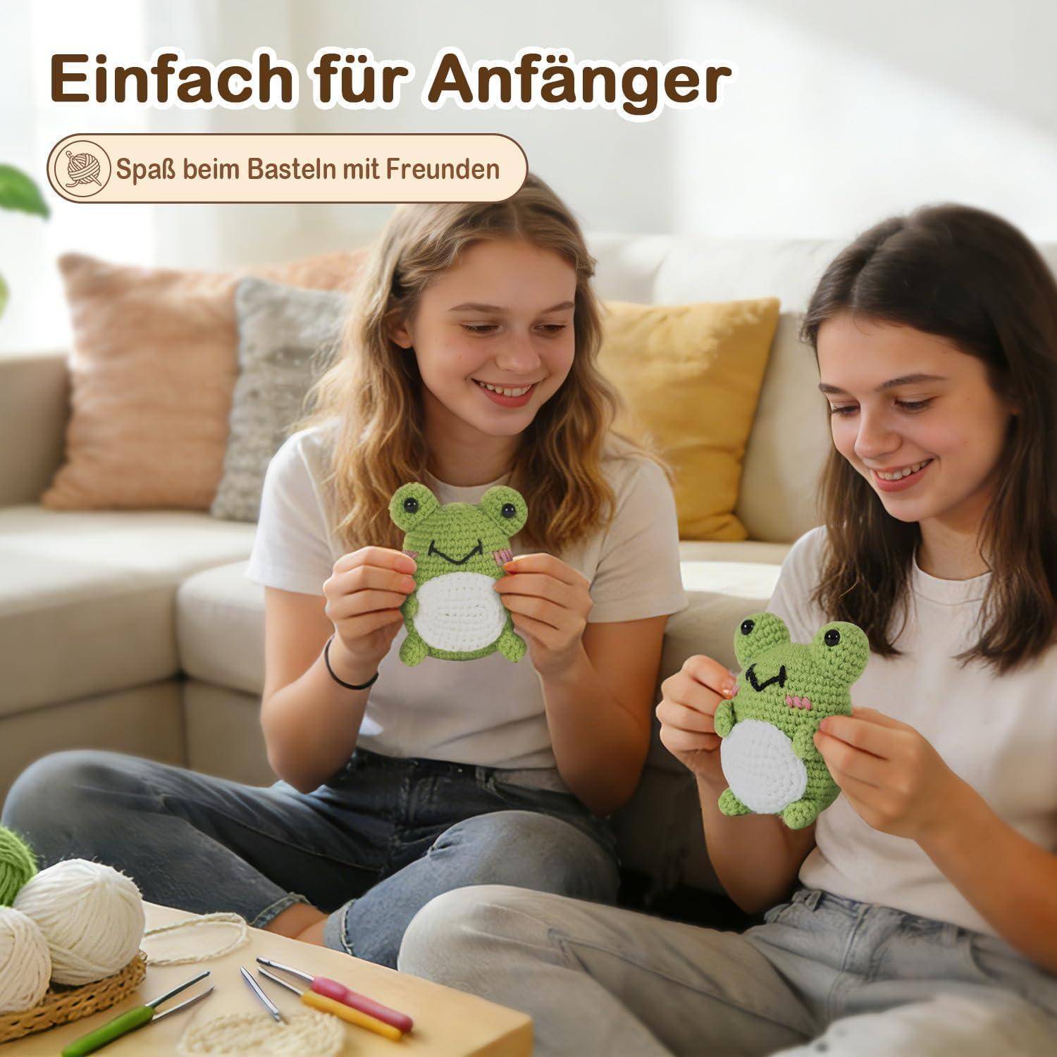 Zwei lächelnde Mädchen auf einem Sofa halten gehäkelte grüne Froschfiguren, mit deutschem Text „Einfach für Anfänger