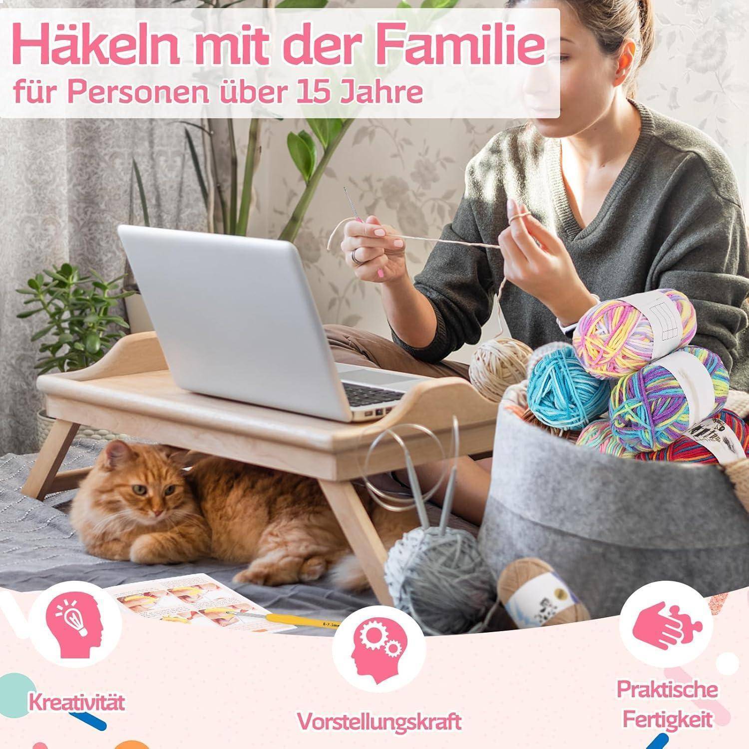 Frau häkelt neben einem Laptop und einem Weidenkorb mit Wolle, mit einer Katze unter dem Tisch; der Text lautet „Häkeln mit der Familie