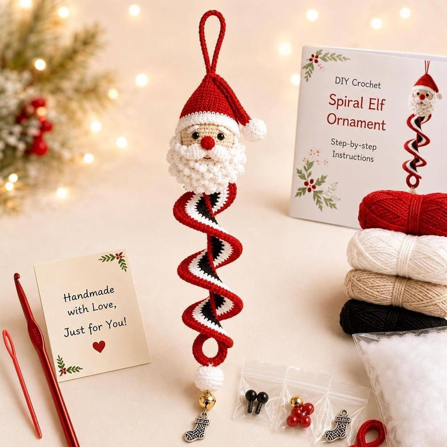 Gehäkeltes Spiral-Elf-Ornament mit Weihnachtsmanngesicht hängt neben einer DIY-Musterschachtel, Garn, Häkelnadeln und einer „Handmade with Love"-Karte.