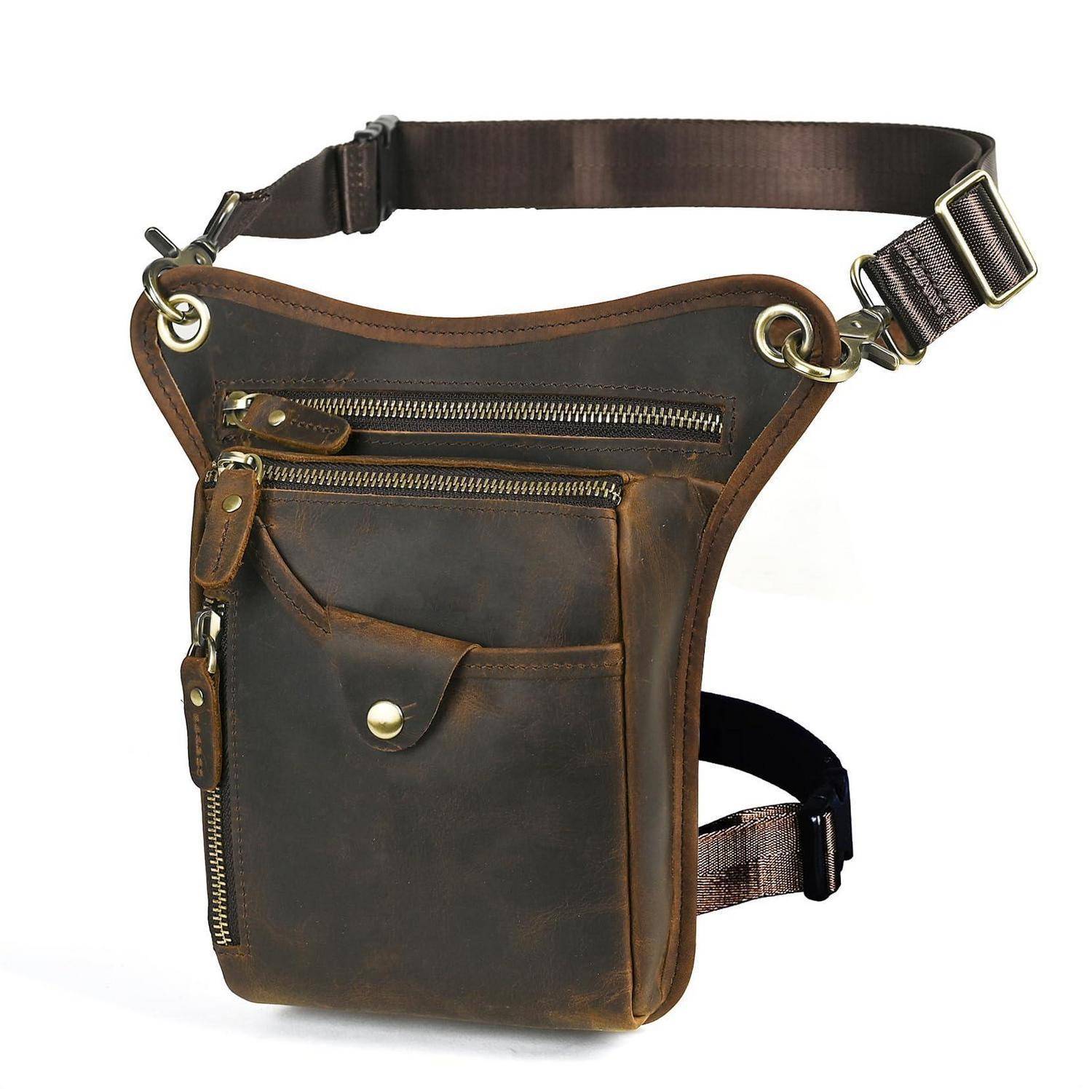 Braune Ledertasche zum Umhängen mit Beinfach, verstellbarem Hüftgurt, vorderen Reißverschlusstaschen und Druckknopftasche auf weißem Hintergrund.