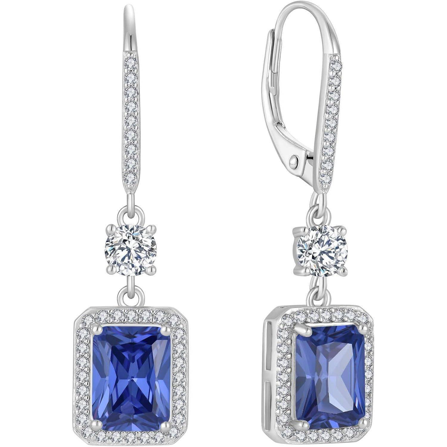 Paar silberner Tropfenohrringe mit blauen rechteckigen Edelsteinen, Pavé-Akzenten und runden diamantähnlichen Steinen auf weißem Hintergrund.