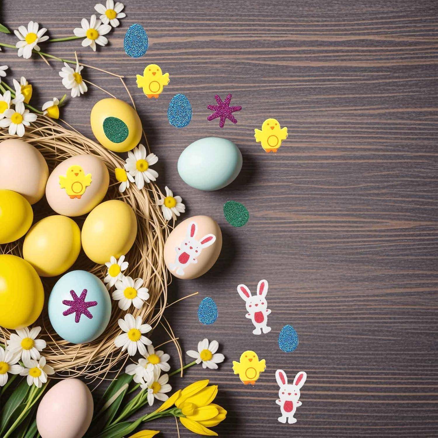 Verzierte Ostereier in einem Strohnest mit Gänseblümchen und Tulpen auf einer Holzoberfläche, mit kleinen Küken- und Hasen-Aufklebern in der Nähe.