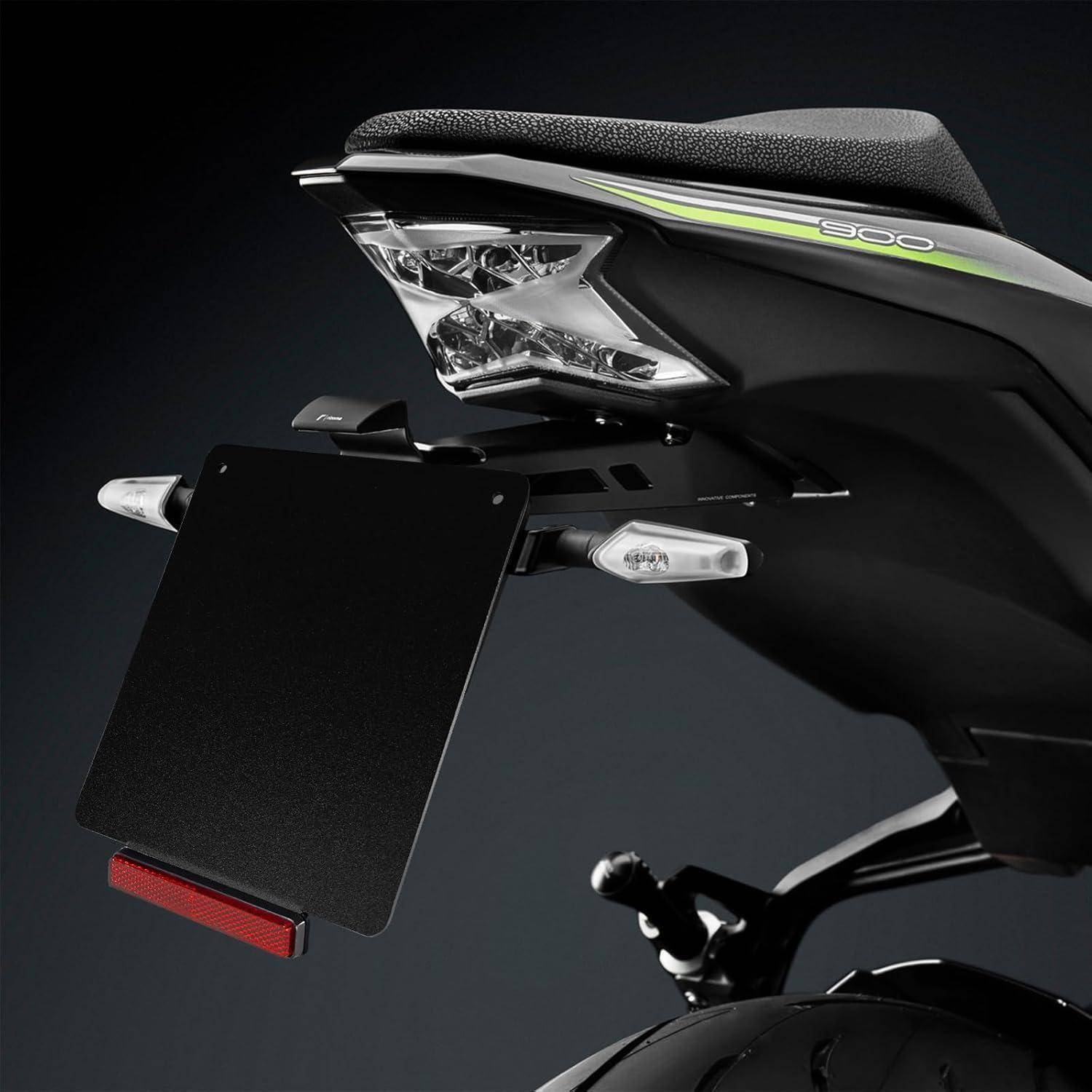 Nahaufnahme eines Motorrad-Hinterteils mit Rücklicht, Blinkern und Kennzeichenhalter vor dunklem Hintergrund.