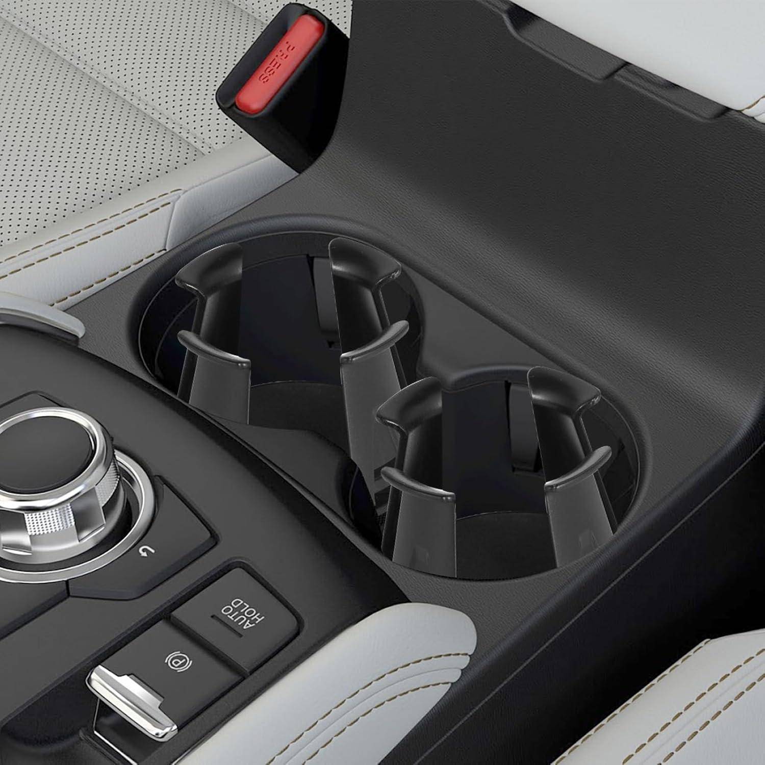 Mittelkonsole des Autos mit zwei Getränkehaltern, einer Auto-Hold-Taste und einem Drehregler neben der Armlehne.
