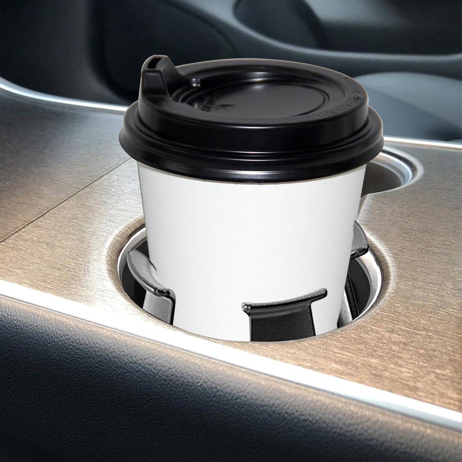 Weißer Kaffee-Behälter zum Mitnehmen mit schwarzem Deckel in einem Getränkehalter für das Auto auf der Mittelkonsole.