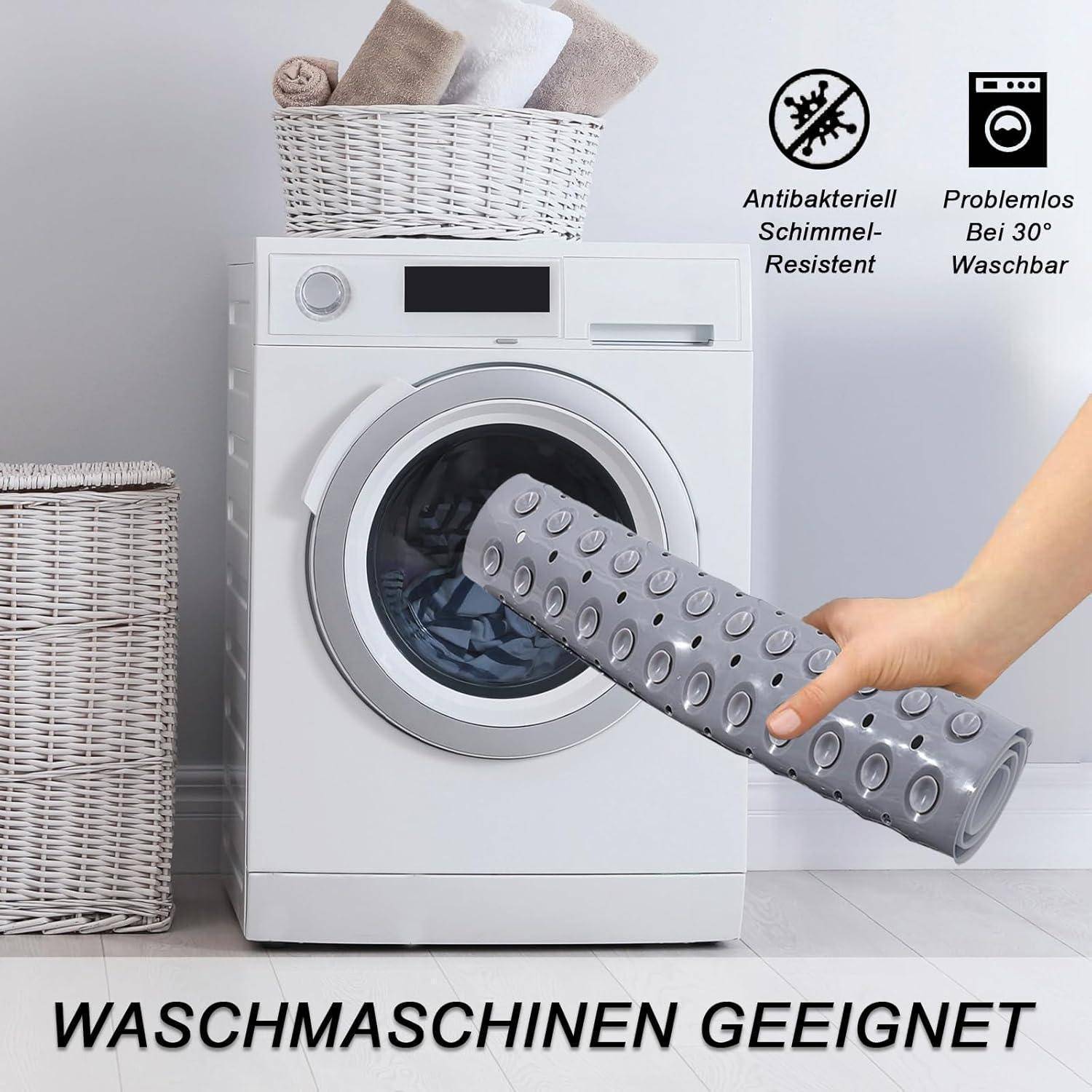Weiße Waschmaschine mit einer Hand, die eine graue rutschfeste Matte einführt; deutscher Text sagt „WASCHMASCHINEN GEEIGNET", „Antibakteriell Schimmel-Resistent"", „Problemlos Bei 30° Waschbar"".