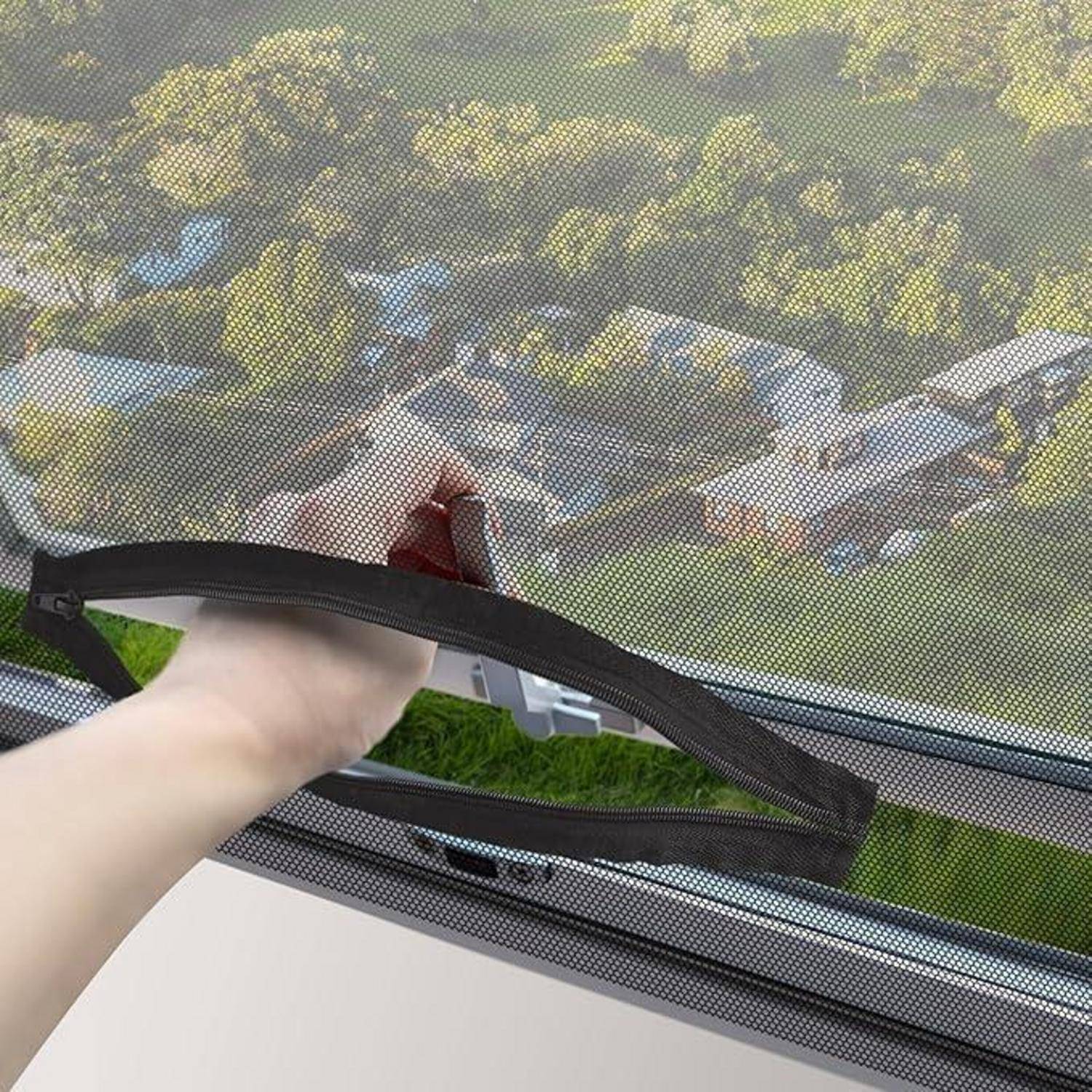 Eine Hand zieht einen schwarzen Reißverschluss auf einem Fensterfliegengitter, wodurch eine Außenansicht von Bäumen und Dächern durch das Maschengewebe sichtbar wird.