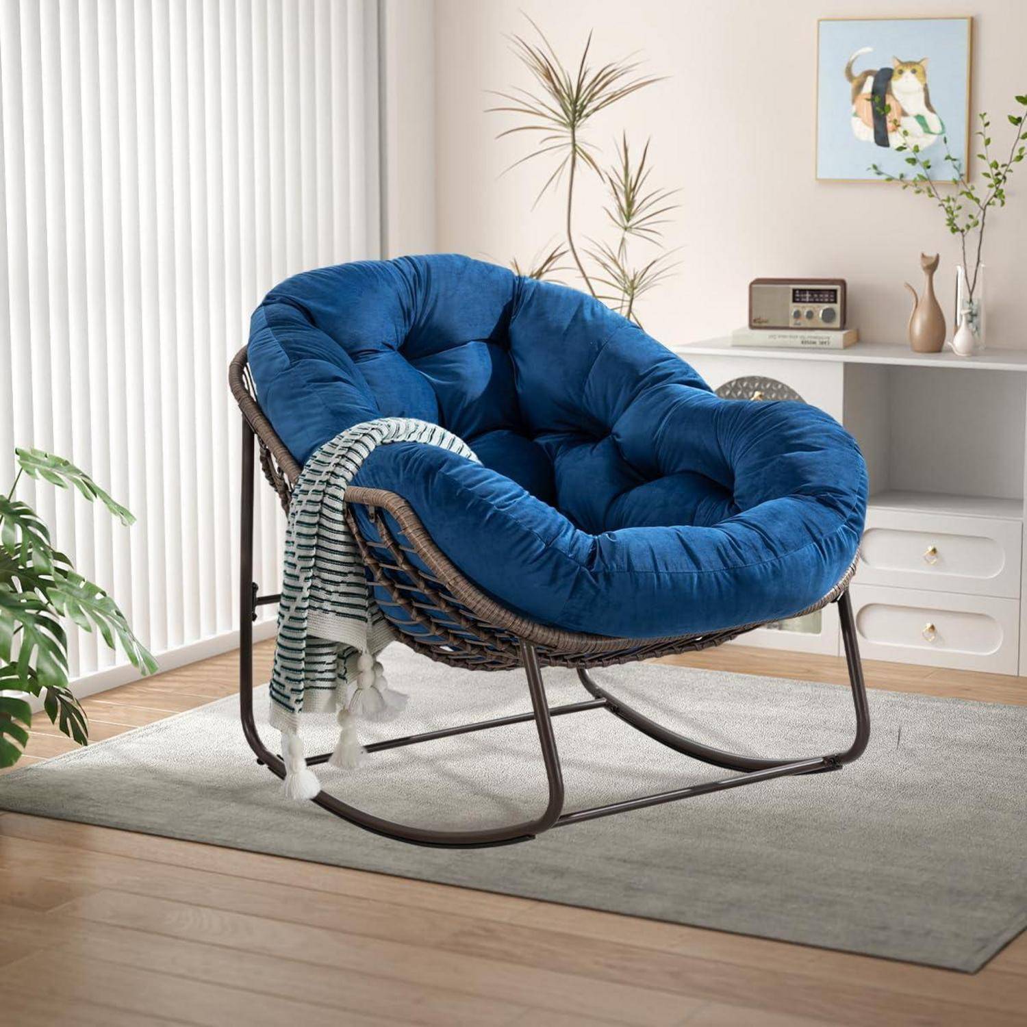 Blauer gepolsterter Papasan-Stuhl mit gestreiftem Überwurf auf einem grauen Teppich in einem hellen Wohnzimmer