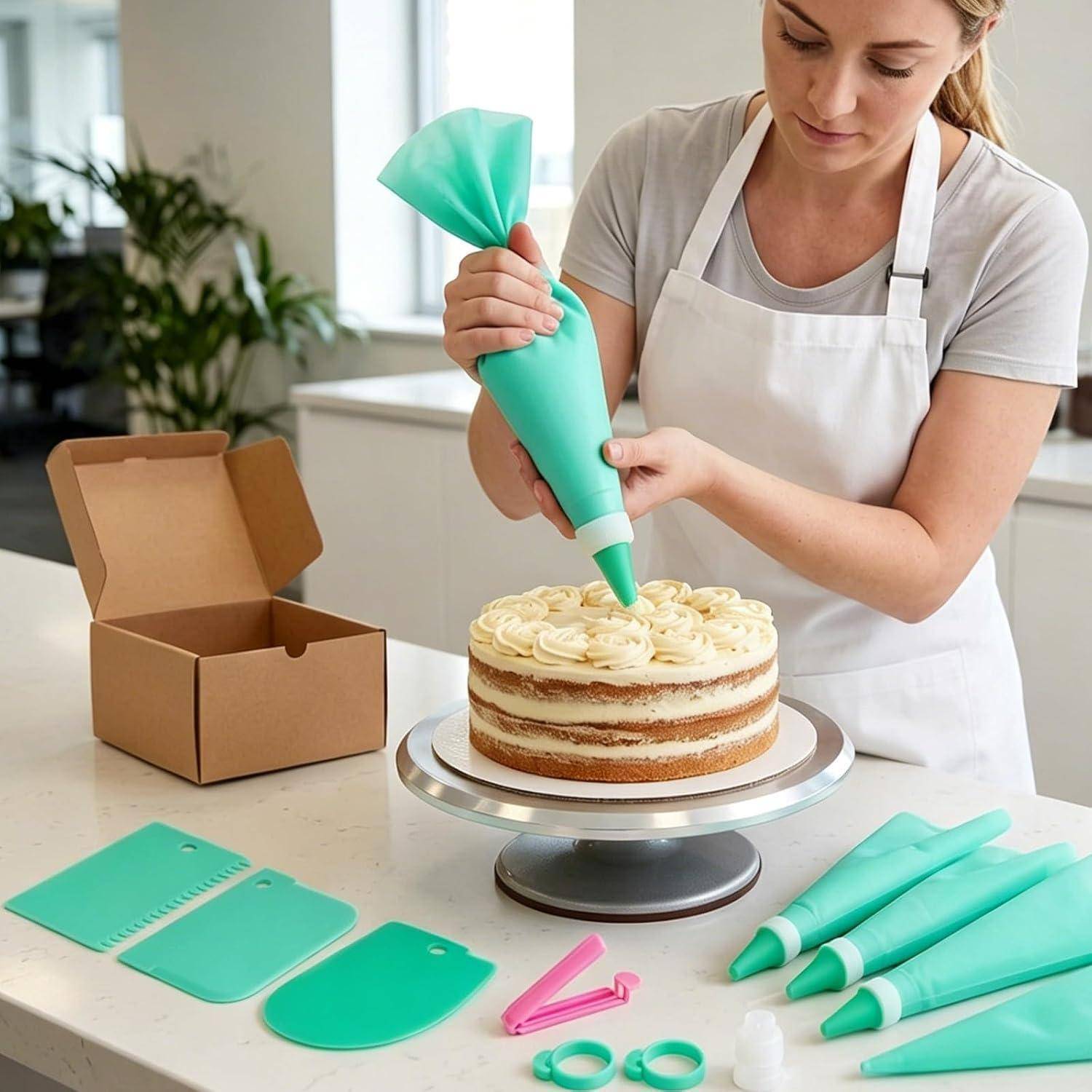 Frau in einer Schürze spritzt Glasur auf einen mehrschichtigen Kuchen in einer Küche, mit Kuchendekorationswerkzeugen und einer offenen Schachtel in der Nähe.