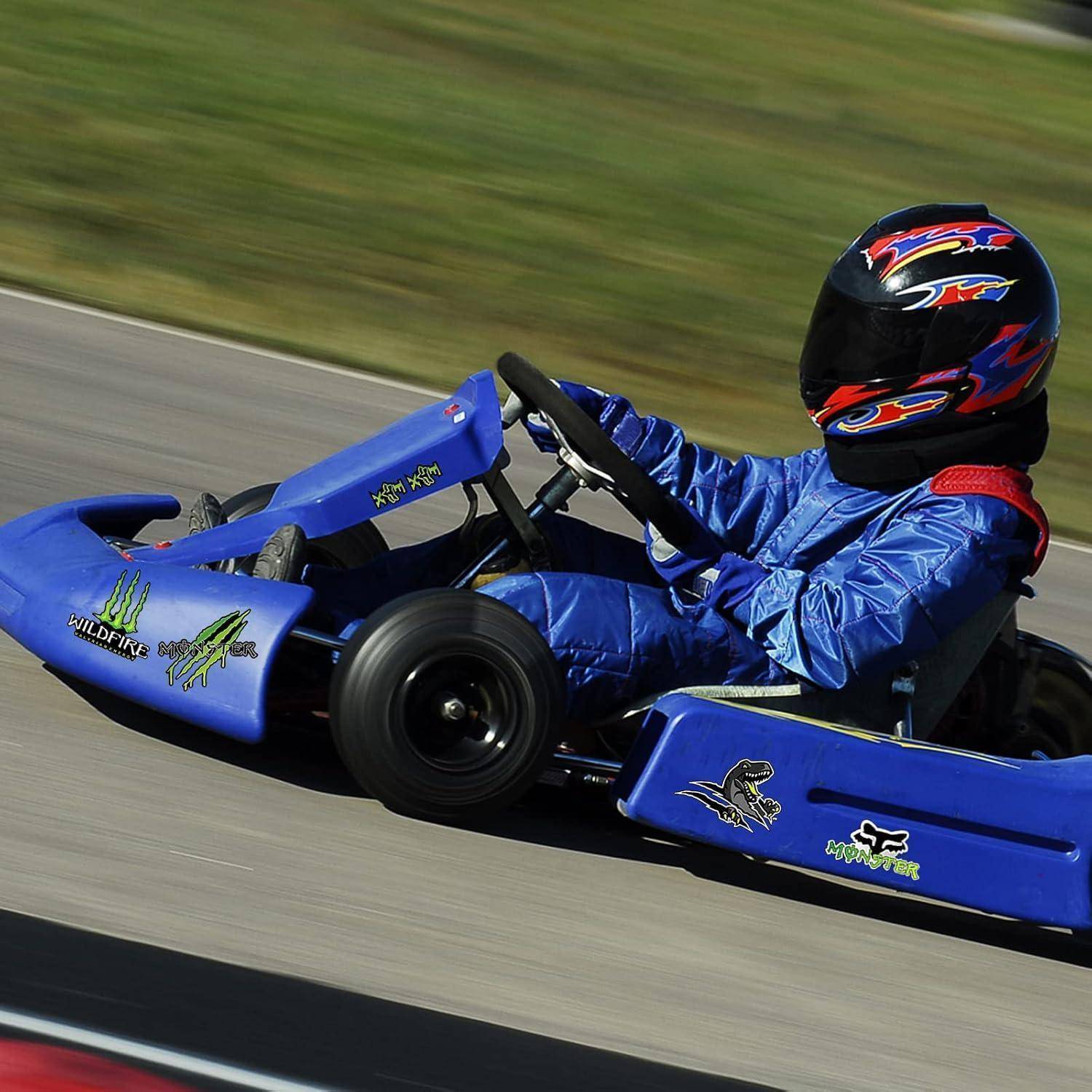 Ein Kind in einem blauen Go-Kart fährt auf einer Strecke, trägt einen schwarzen Helm und einen blauen Anzug.