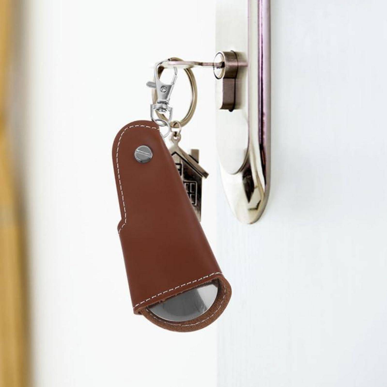 Nahaufnahme eines braunen Leder-Schlüsselanhängers, der an einem Schlüsselhaken an einer weißen Wand hängt.