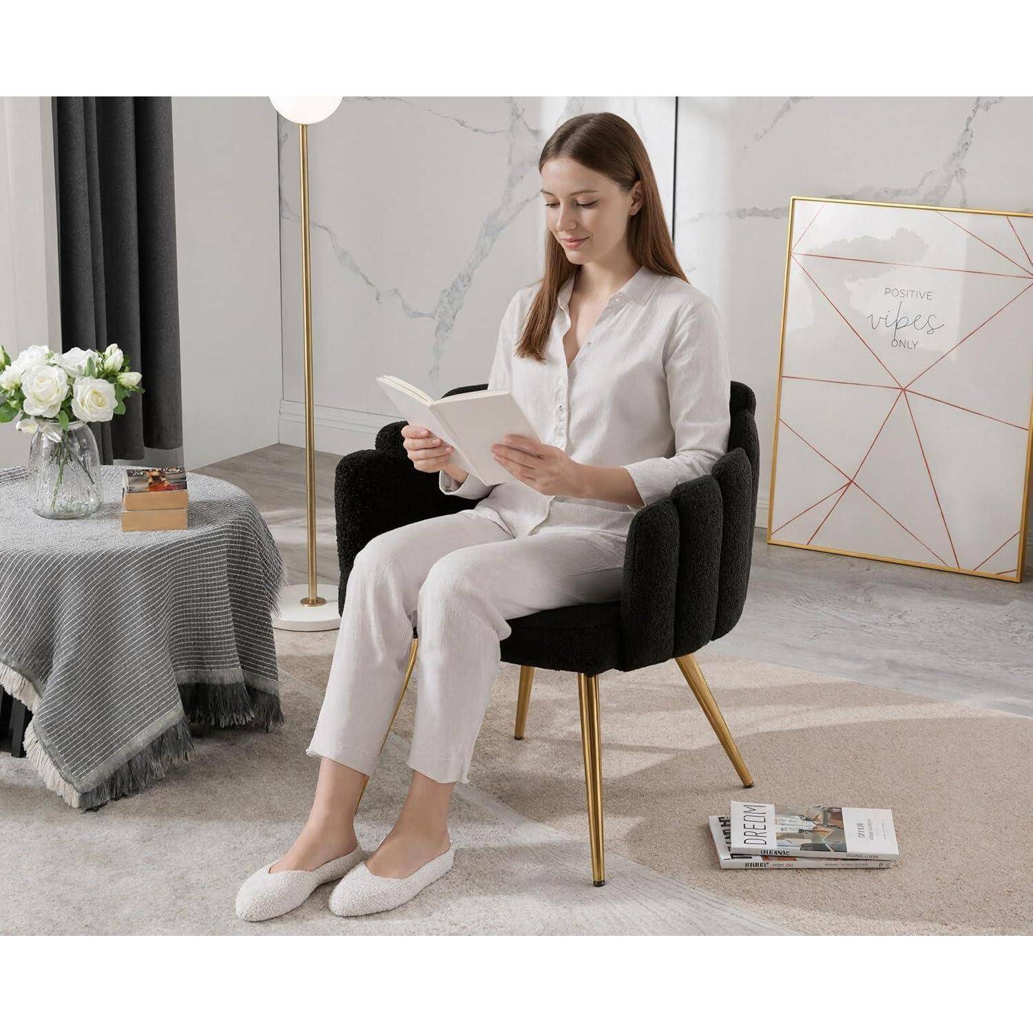 Frau in weißer Loungewear sitzt in einem schwarzen Stuhl und liest ein Buch in einem hellen, stylisch eingerichteten Wohnzimmer.