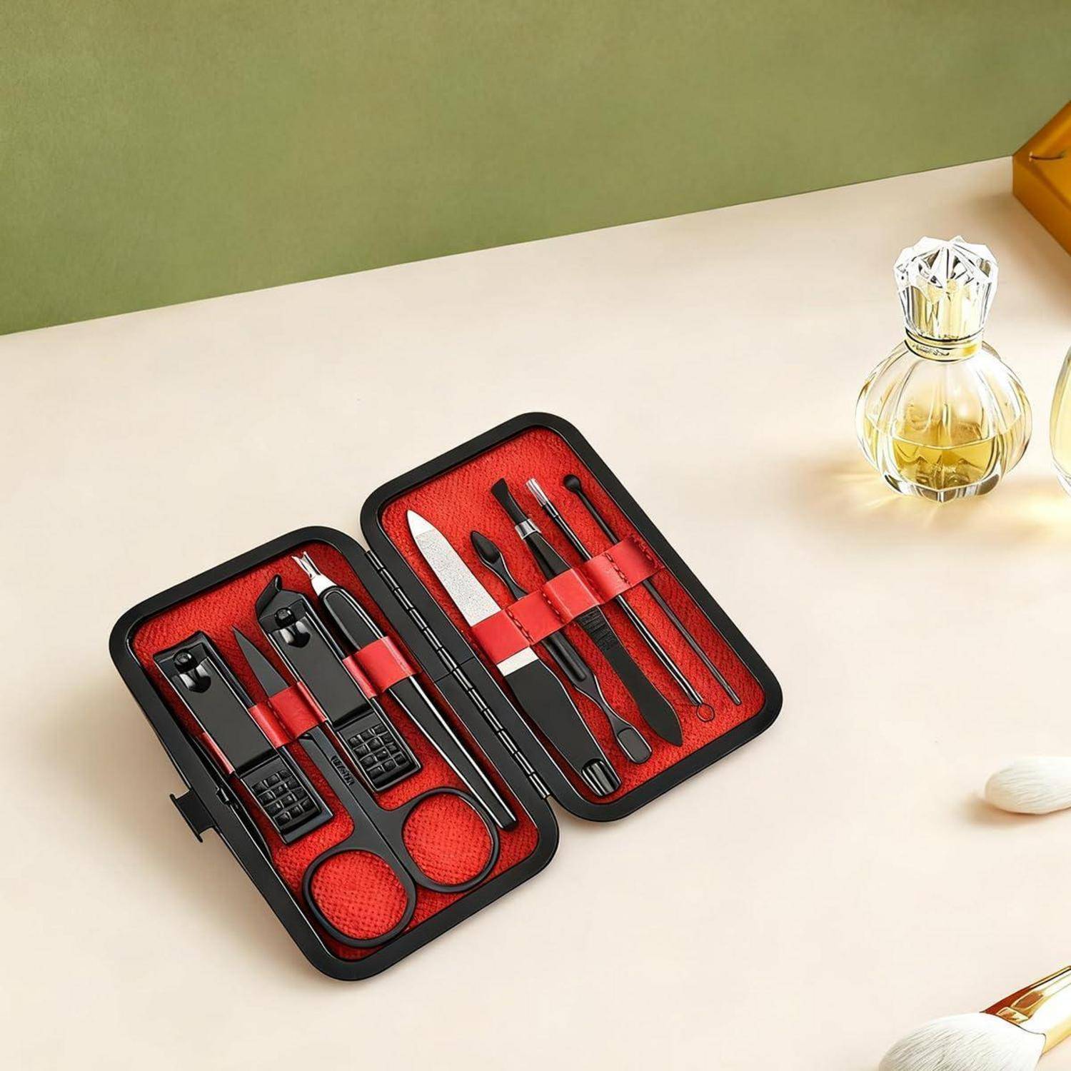 Offenes Maniküre-Set mit Nagelknipsern, Schere, Pinzette, Feile und Nagelhaut-Werkzeugen, angeordnet in einem schwarzen Etui mit rotem Futter.