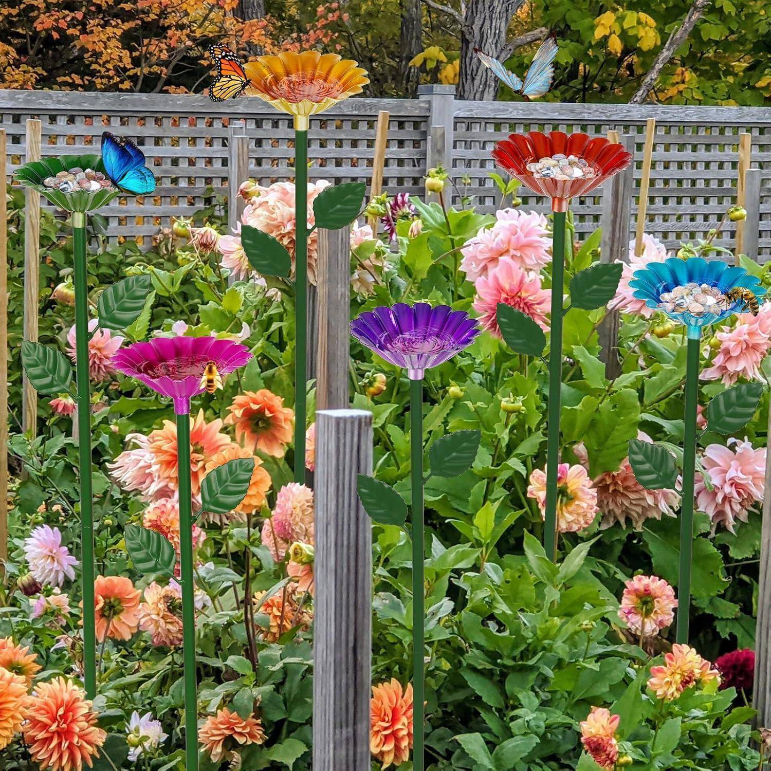 Bunte Gartenszene mit mehrfarbigen blütenförmigen Windrädern zwischen blühenden Blumen und grünem Laub in einem eingezäunten Hinterhof.