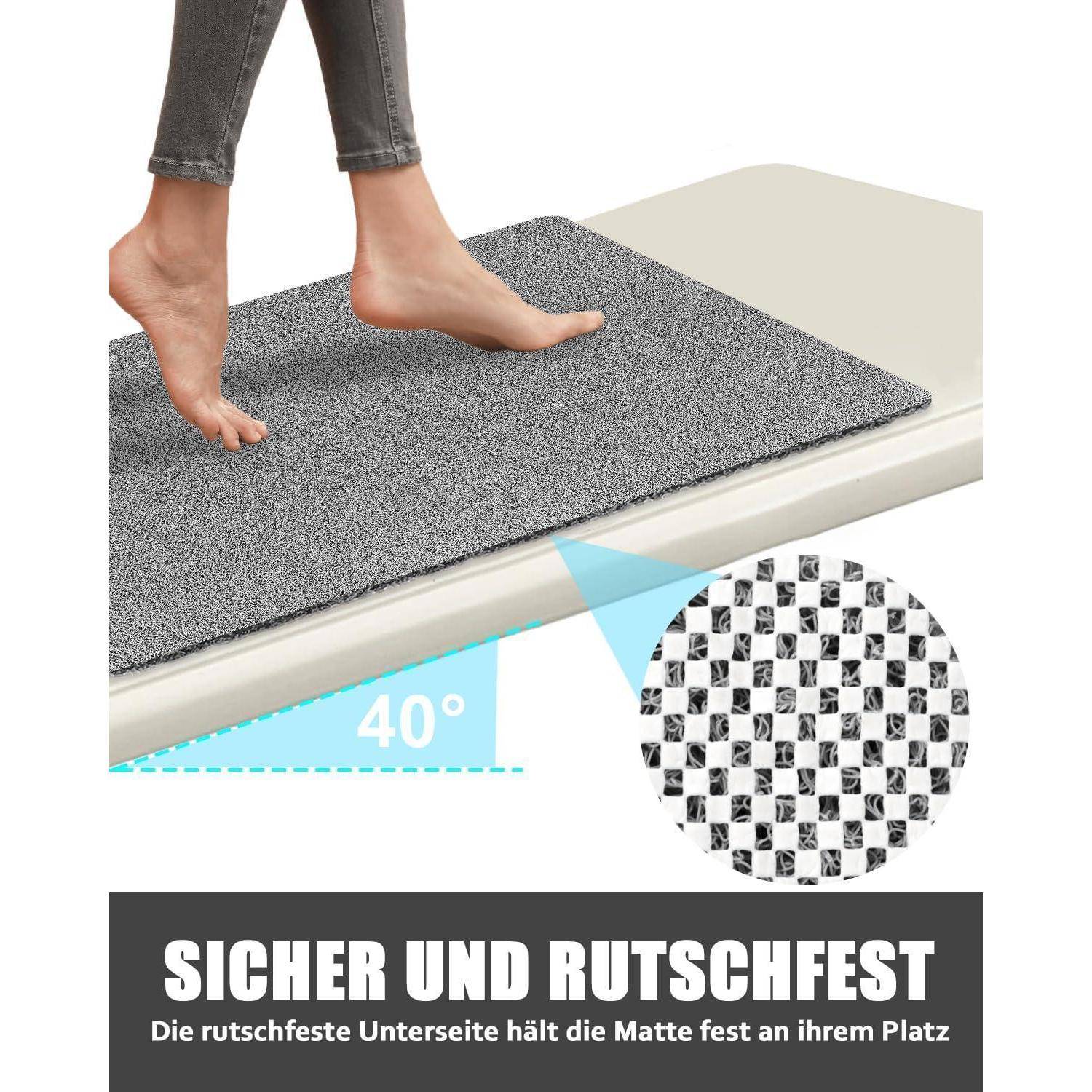 Füße treten auf eine graue rutschfeste Matte am Bodenrand, beschriftet mit „40°"; die Einstellung zeigt die strukturierte Rückseite mit deutschem Text „SICHER UND RUTSCHFEST"", was anzeigt, dass die Matte sicher an Ort und Stelle bleibt.