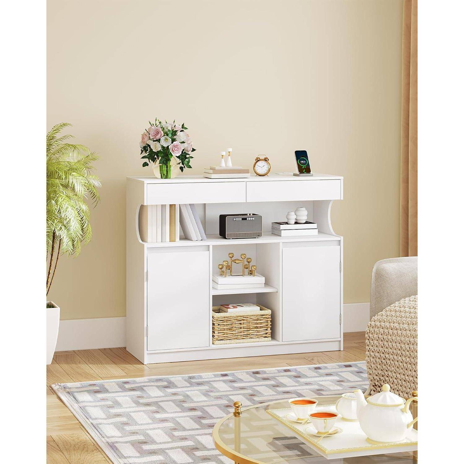Weißes Sideboard-Schrank in einem beigefarbenen Wohnzimmer mit offenen Regalen, Schiebetüren und Dekoration oben, einschließlich Blumen, einer Uhr und einem Rahmenbild.