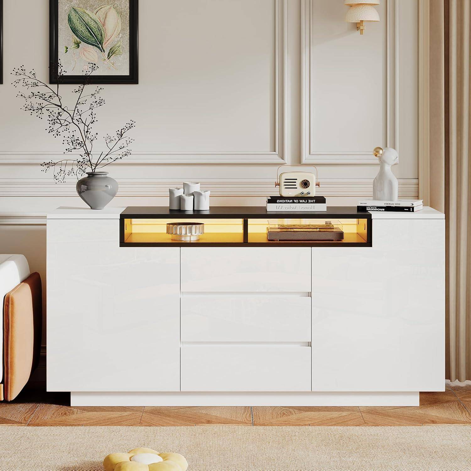 Modernes weißes Sideboard mit zentralen Schubladen und bernsteinfarben beleuchteten Ausstellungsregalen, gestylt mit Vasen, Büchern und Dekoration in einem hellen Wohnzimmer.