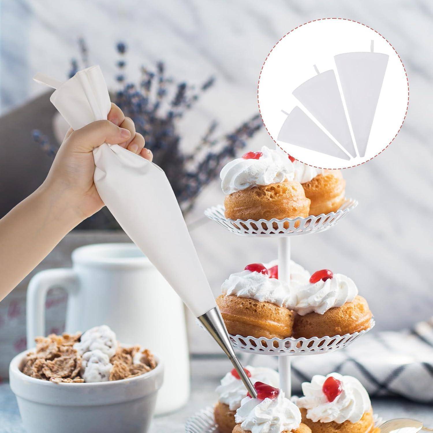 Eine Hand hält einen Spritzbeutel, um kleine Kuchen mit Schlagsahne und Kirschen auf einem gestuften Desserttablett zu dekorieren; eine Nahaufnahme zeigt die Form der Spritzbeutelöffnung.