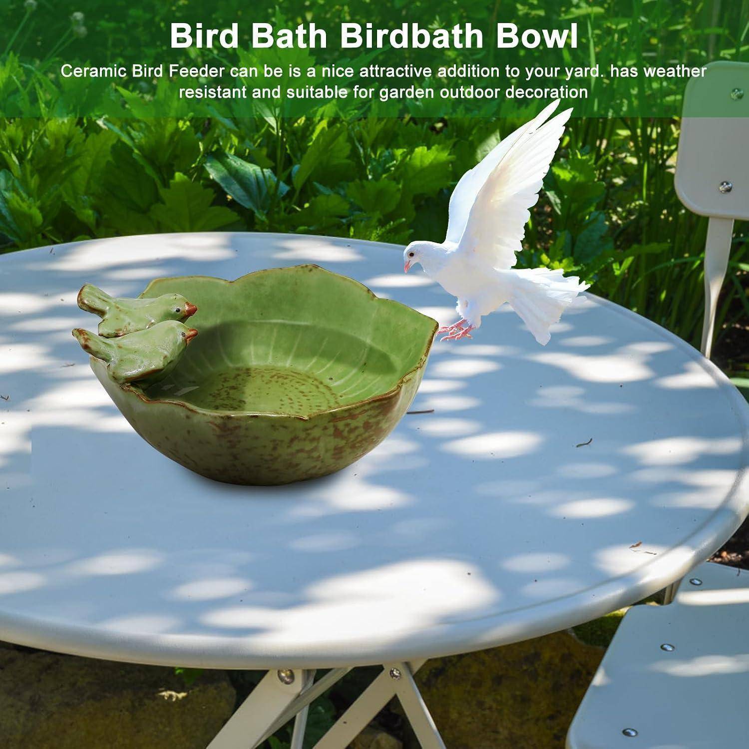 Keramikbadeschale für Vögel auf einem runden weißen Tisch in einem Garten, mit einer weißen Taubenfigurine, die daneben fliegt; der Text lautet „Bird Bath Birdbath Bowl".
