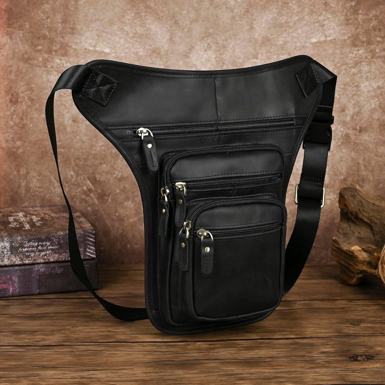Schwarze Lederslingtasche mit mehreren mit Reißverschluss versehenen vorderen Taschen, präsentiert auf einer Holzoberfläche vor einem gesprenkelten Hintergrund.