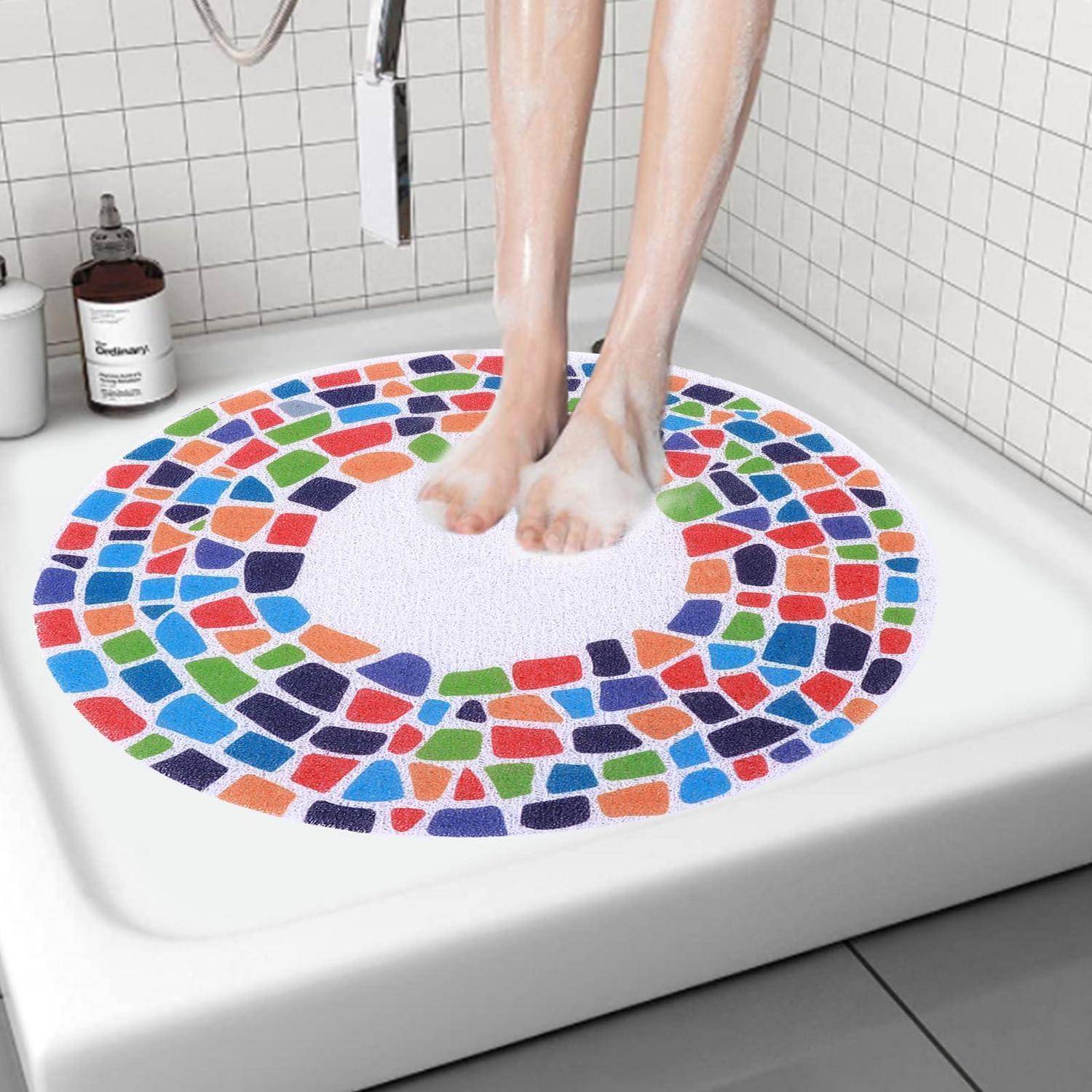Person, die in einer Dusche auf einer farbenfrohen Mosaik-Muster-Antirutschmatte in einem gekachelten Badezimmer steht.