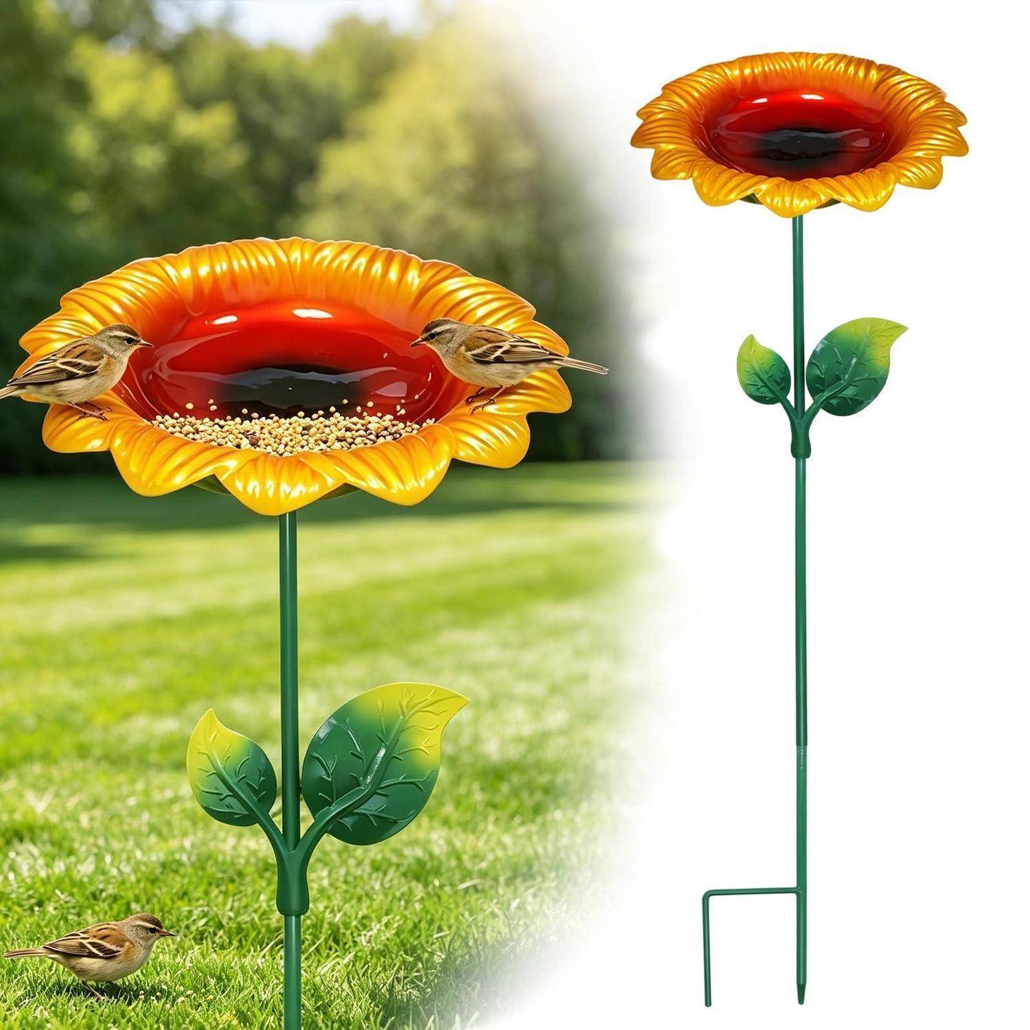 Zwei kleine Vögel sitzen auf einem sonnenblumenförmigen Vogelfutterhaus auf einem Metallstab, gezeigt in einer Gartenumgebung mit einem zweiten höheren Futterhaus daneben.