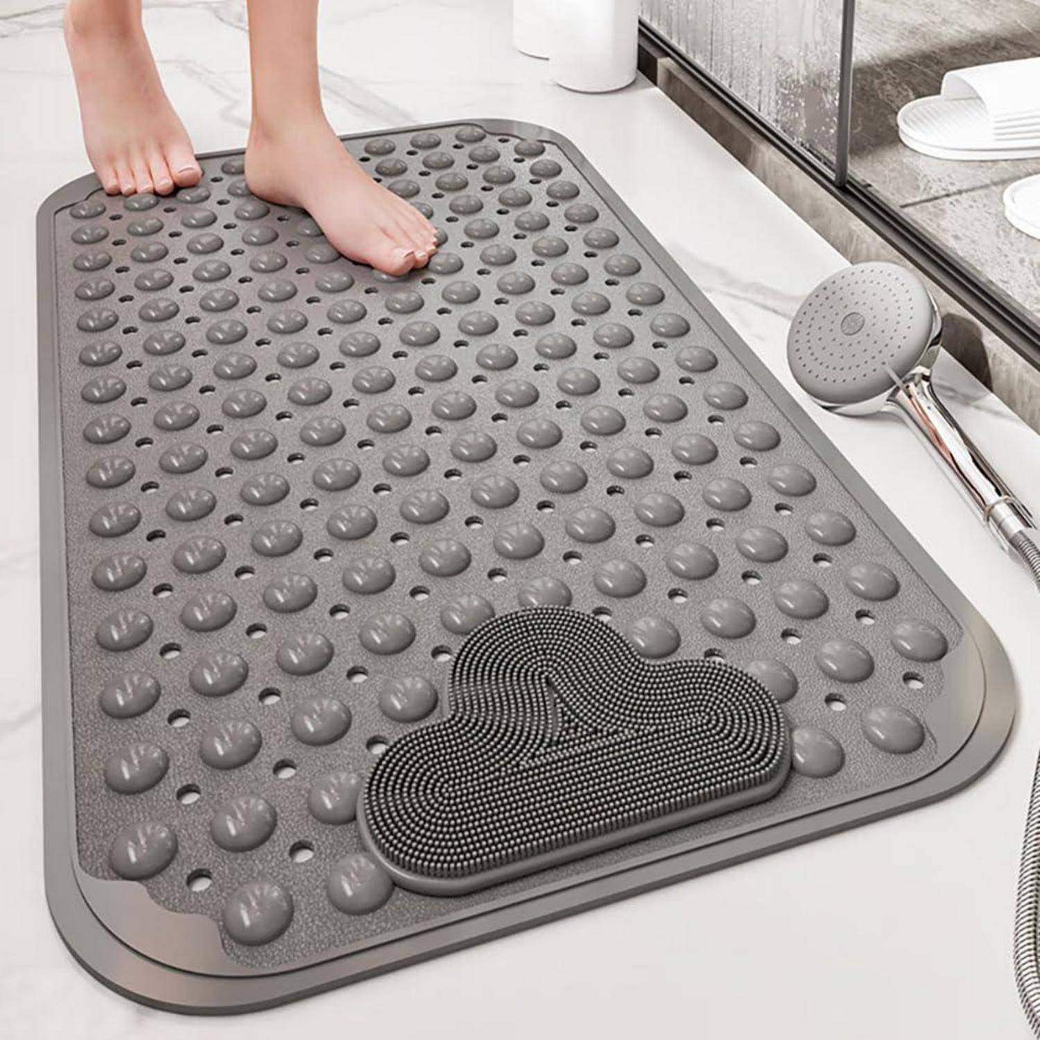 Füße stehen auf einer grauen strukturierten Badmatte mit erhabenen Noppen und einem abnehmbaren schwarzen Schrubberpad in einem Badezimmer.