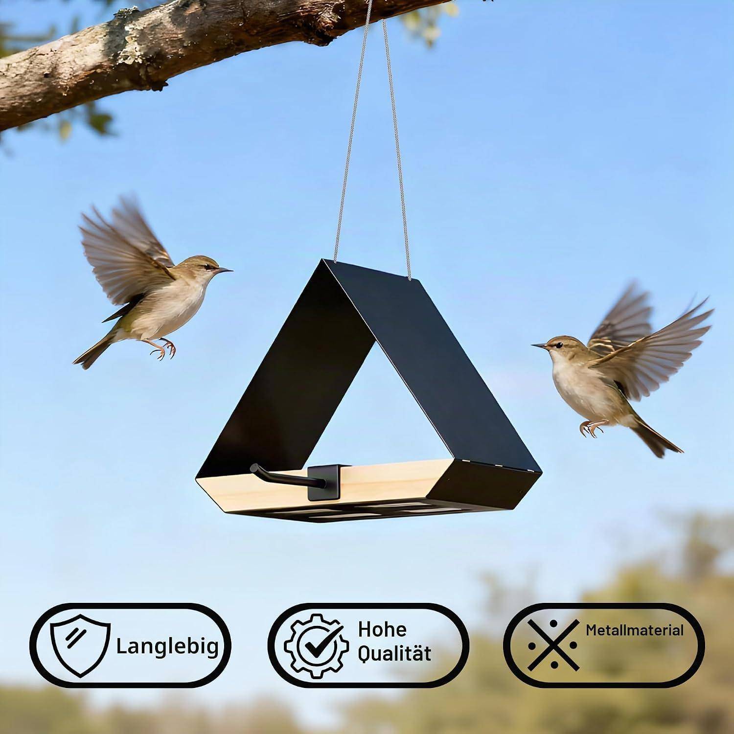 Zwei kleine Vögel schweben neben einem hängenden schwarzen dreieckigen Vogelfutterhaus; deutsche Symbole darunter lesen sich „Langlebig