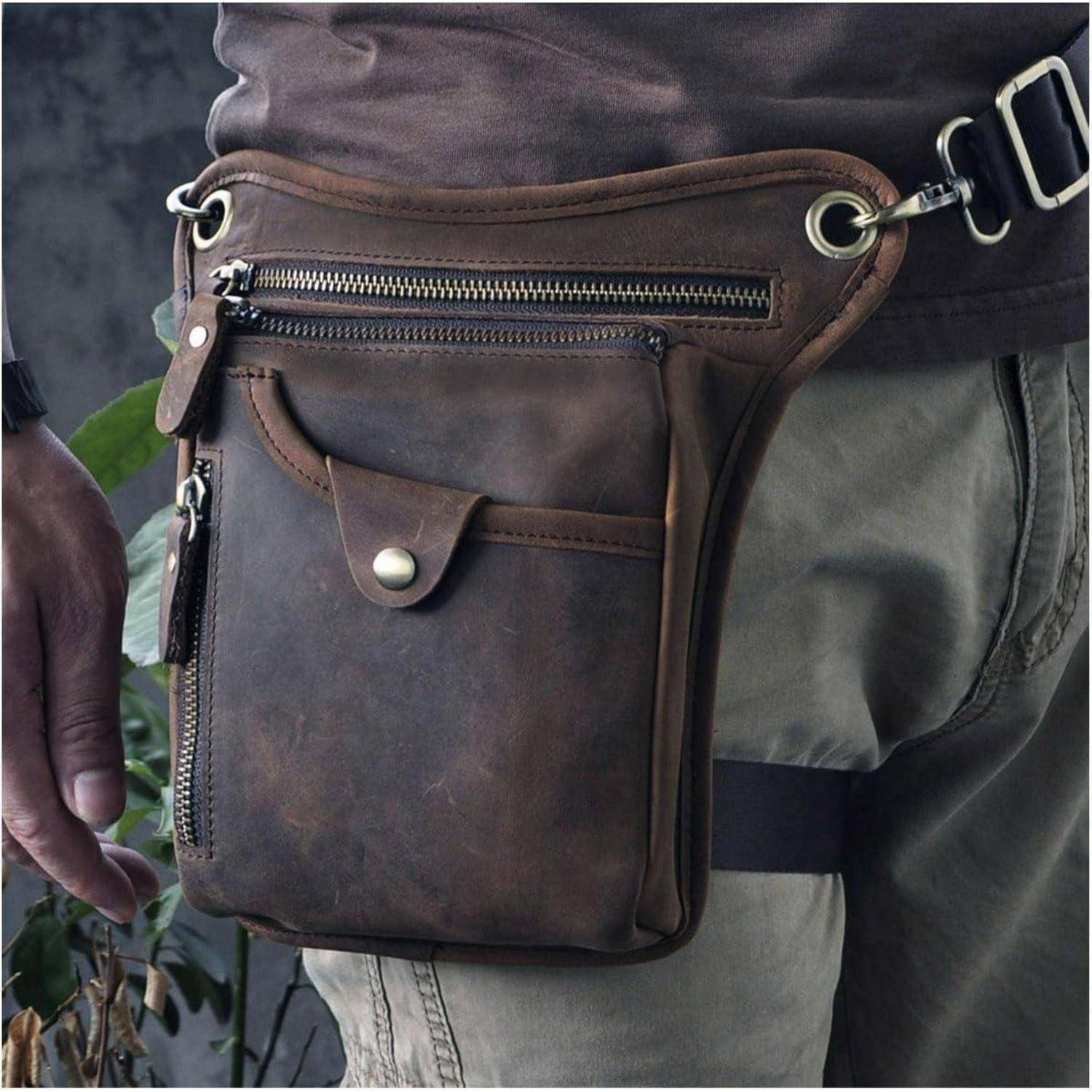 Nahaufnahme einer Person, die eine braune Lederhüfttasche mit mehreren Reißverschlusstaschen und einer Klapptasche an der Hüfte trägt.