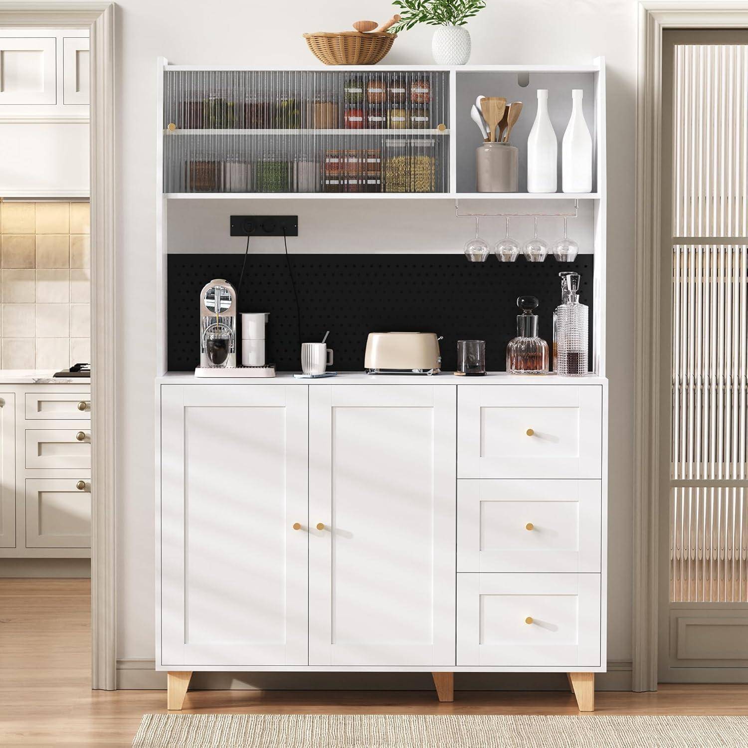 Weißer Küchenschrank mit offenen Regalen, Glaswaren, Flaschen, Toaster, Kaffeemaschine und Schubladen vor einer schwarzen Rückwand in einer hellen Küche.