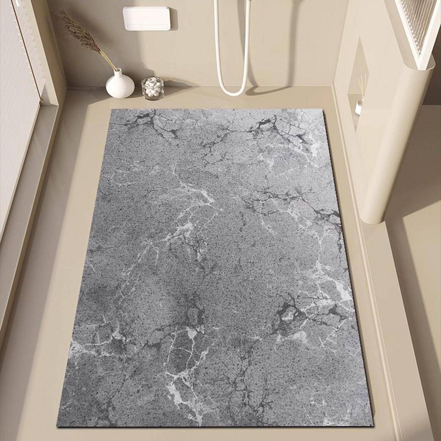 Badevorleger mit grauem Marmor-Design auf einem beigen Badezimmerboden unter einem Waschbecken und einer Toilette, gezeigt in einem kleinen Badezimmer.