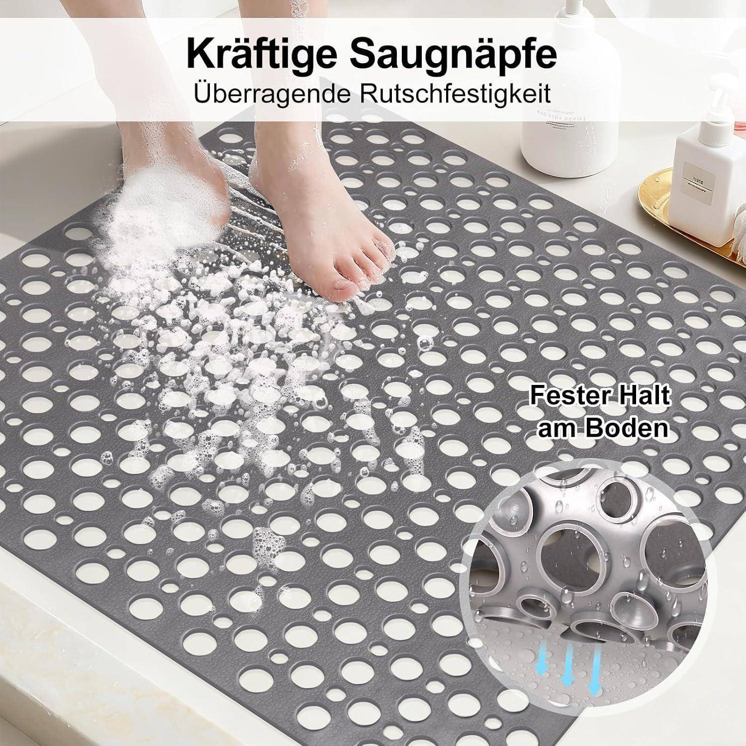 Ein Fuß reibt eine graue Badematte mit starkem Saugnapfgriff, gezeigt mit deutschem Text 'Kräftige Saugnäpfe' und 'Fester Halt am Boden'.