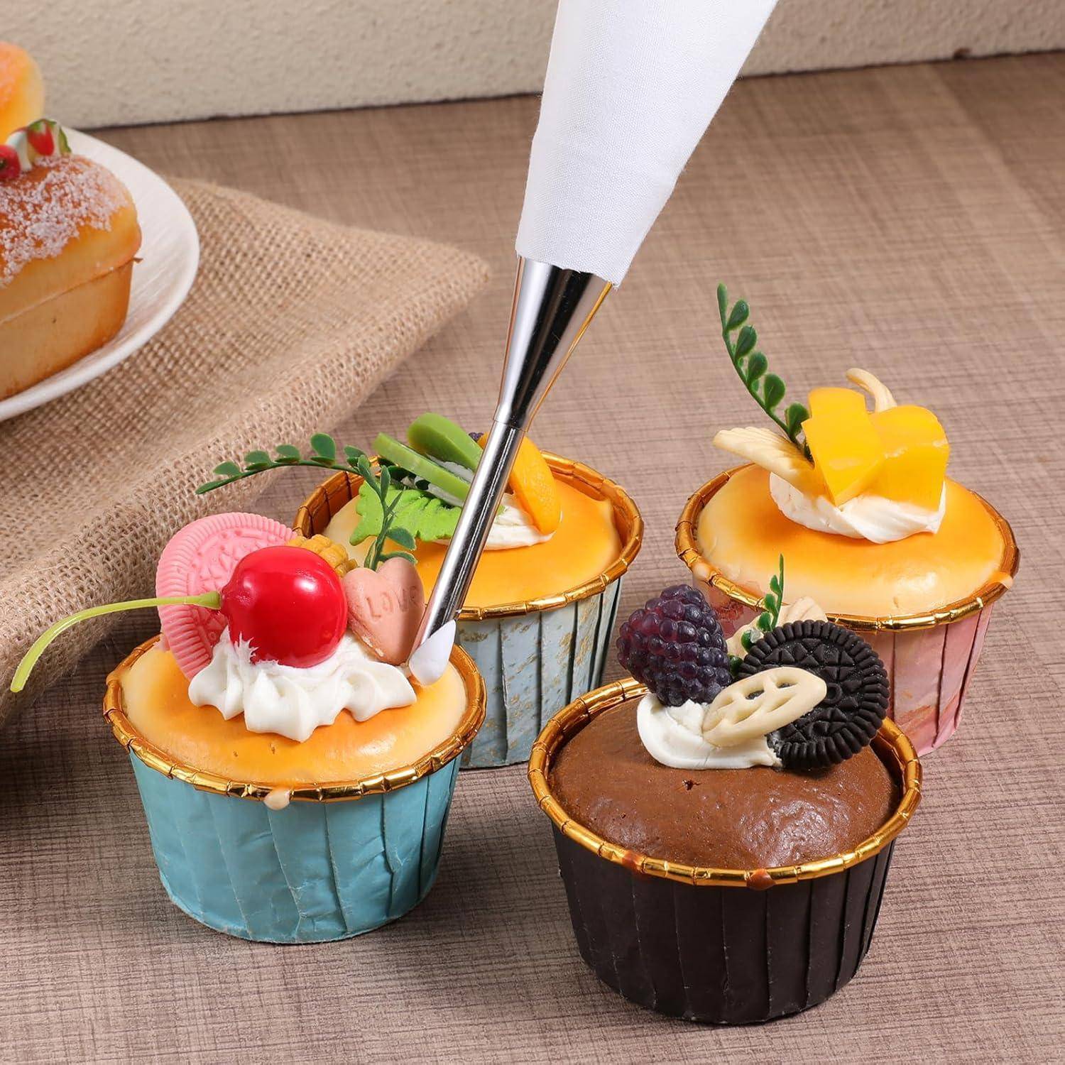 Konditormeister, der weiße Creme mit einem Spritzbeutel auf verschiedenfarbige kleine Törtchen und Cupcakes auf einem Tisch spritzt.